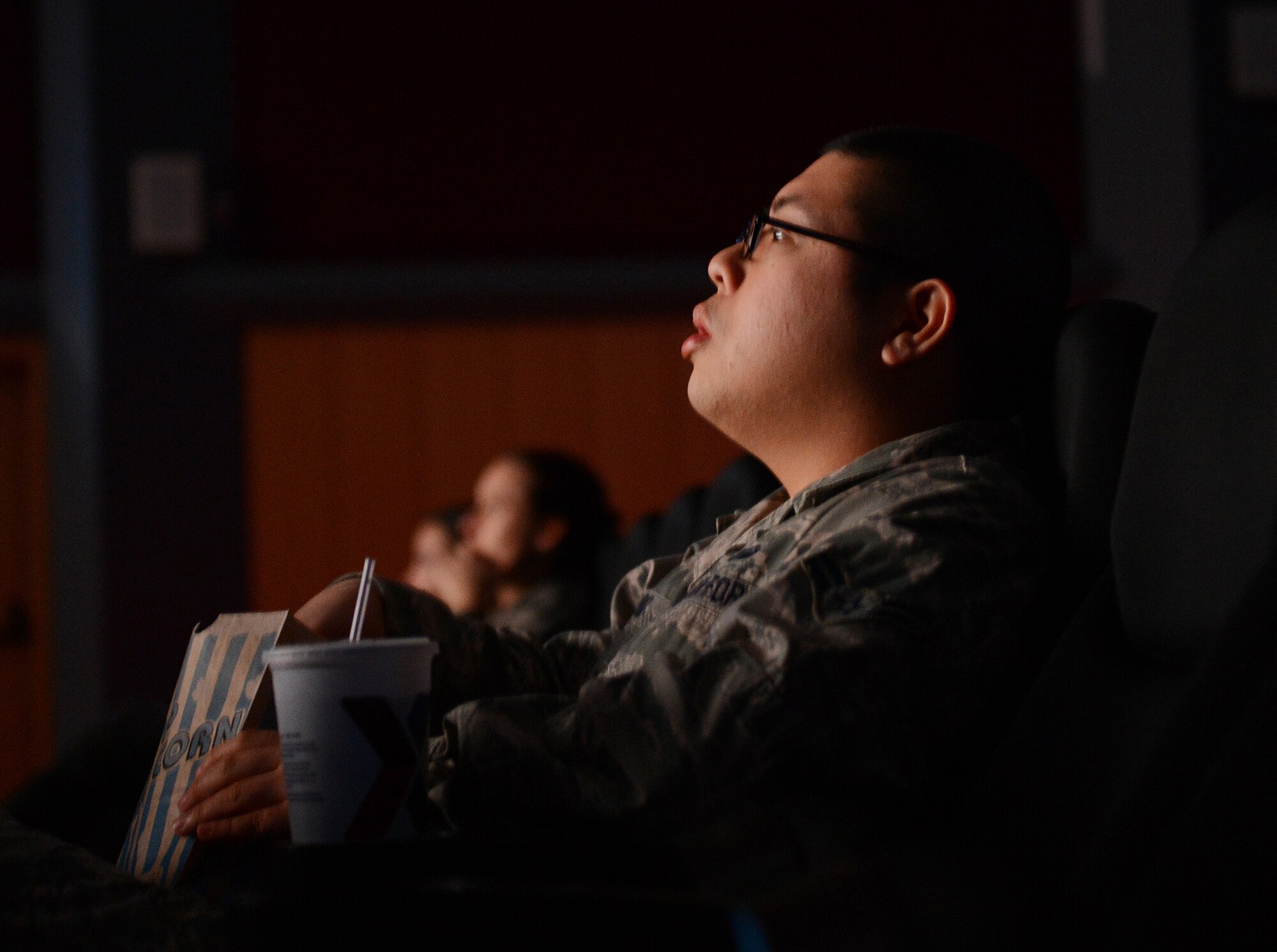 U.S. Air Force Airman 1st Class Jan-Michael Cruz, 52nd Fighter Wing command section executive administrator, watches the documentary film "Ghost Army" in the Skyline Theater at Spangdahlem Air Base, Germany, March 11, 2014. The World War II documentary chronicles the history of a secret U.S. Army unit whose mission was to mislead and deceive the enemy with various tactics including recorded battle sounds, inflatable tanks and false radio traffic. (U.S. Air Force photo by Staff Sgt. Chad Warren/released)