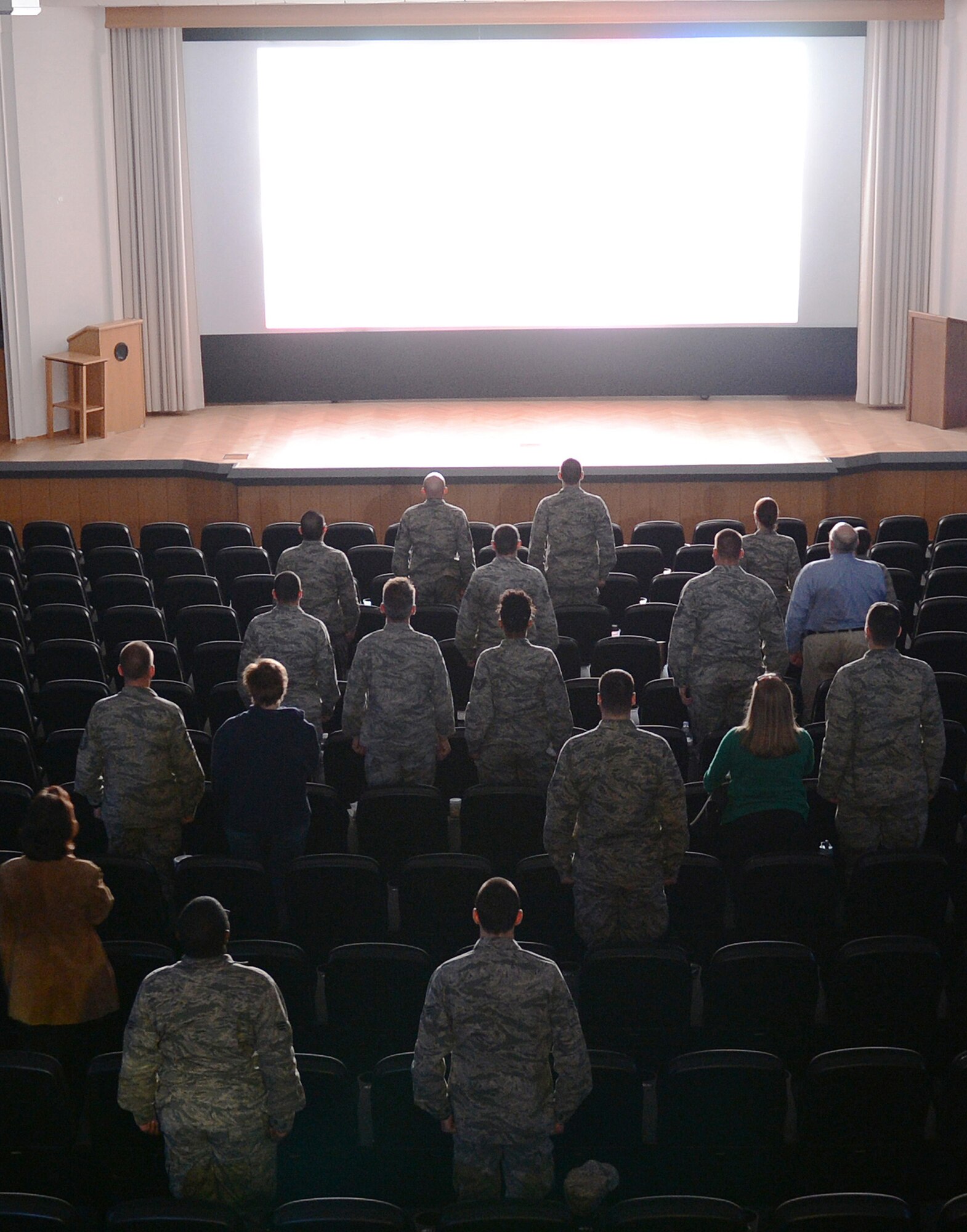 Patrons stand for the national anthem before the showing of "Ghost Army" in the Skyline Theater at Spangdahlem Air Base, Germany, March 11, 2014. The documentary chronicles the history of a secret World War II U.S. Army unit whose mission was to mislead and deceive the enemy with various tactics including recorded battle sounds, inflatable tanks and false radio broadcasts. (U.S. Air Force photo by Staff Sgt. Chad Warren/released)