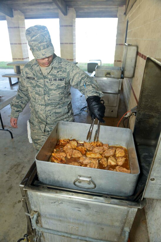 U.S. Air Force Airman 1st Class Theresa Tennerson, 136th Force Support Squadron, Services Flight, Texas Air National Guard, prepares barbecue chicken in a M-59 oven-field range unit at Naval Air Station Fort Worth Joint Reserve Base, Texas, Feb. 22, 2014. Use of the oven-field range unit dates back to the Korean war. (Air National Guard photos by Master Sgt. Charles Hatton/Released)