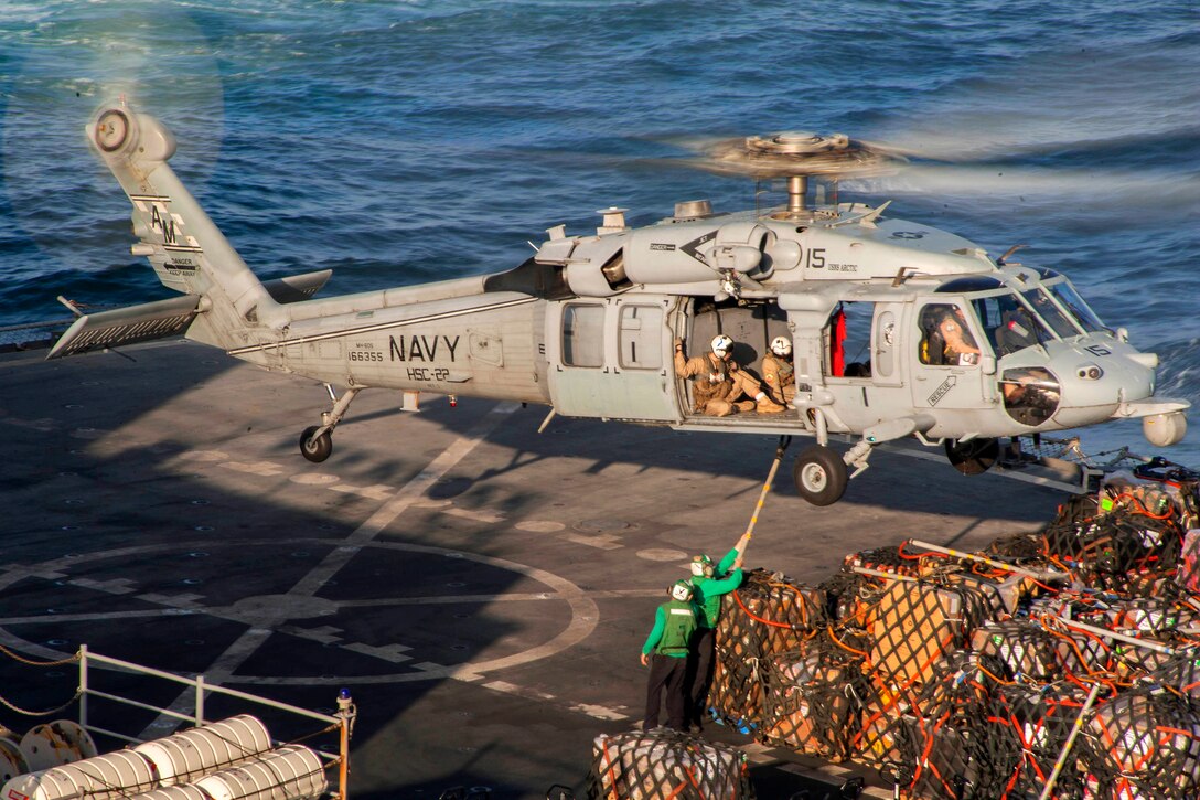 U.S. sailors attach cargo to an MH-60S Seahawk helicopter for transport from the Military Sealift Command fast combat support ship USNS Arctic to the aircraft carrier USS Harry S. Truman during a replenishment in the Gulf of Oman, March 7, 2014. The helicopter is assigned to Helicopter Sea Combat Squadron 22.