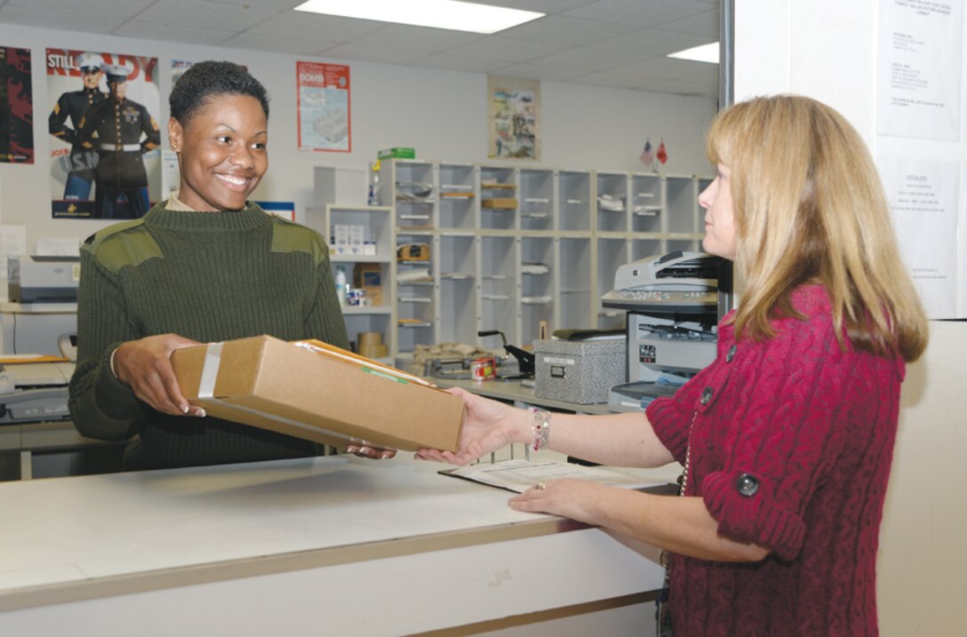 Sgt. Stephanie Bowens, postal clerk, Marine Corps Logistics Base Albany, gives a package to Becky Barrow, data management specialist, Marine Corps Logistics Command, March 7.