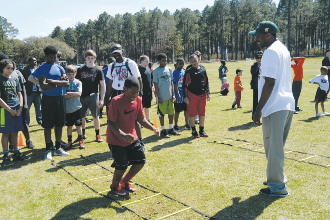 Micaiah Myles (left) from Dothan, Ala., practices speed and agility drills as Green Bay Packers Super Bowl Champion Eric Matthews (right) watches. Matthews, several former National Football League football players and college football coaches taught about 70 youth March 8 at Marine Corps Logistics Base Albany during the 2014 Lee County Warriors Youth Football and Cheer Camp. 