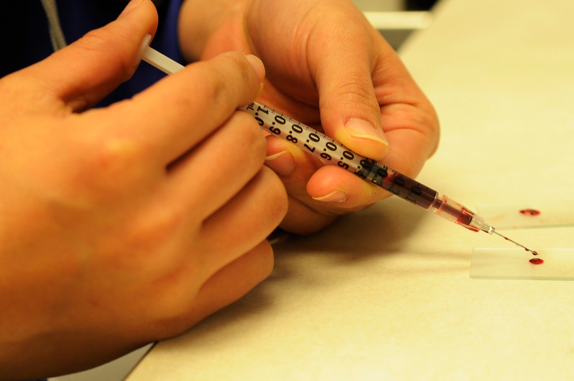 Juri Tedokon, a local Okinawa City intern, practices making a blood smear in the Army veterinary clinic on Kadena Air Base, Japan, March 13, 2014. More than 20 lab technicians and seven veterinarians work with 60 to 100 animals daily and provide care to 50 military working dogs from the Air Force and Marine Corps on Okinawa. (U.S. Air Force photo by Senior Airman Marcus Morris)