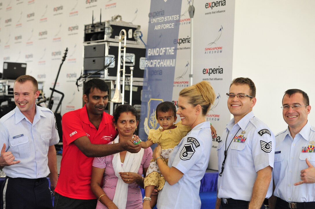 CHANGI, Singapore-- MSgt Lara Murdzia holds a beautiful baby girl as the band poses for some photos with audience members after the show, Feb. 12, 2014.The group played 9 shows to over 100K audience members throughout their tour. The Band of the Pacific-Hawaii went to Singapore in support of the air show, the U.S. Embassy, and to improve international relations. (US Air Force Photo/ SrA Andy Detra/released)