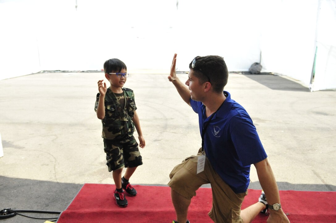 CHANGI, Singapore--  One of newest members of the band, SrA Andy Detra, gives a high-five to a young boy at the Singapore Air Show, Feb. 16, 2014.The group played 9 shows to over 100K audience members throughout their tour. The Band of the Pacific-Hawaii went to Singapore in support of the air show, the U.S. Embassy, and to improve international relations. (US Air Force Photo/ SSgt Courtney Clifford/released)