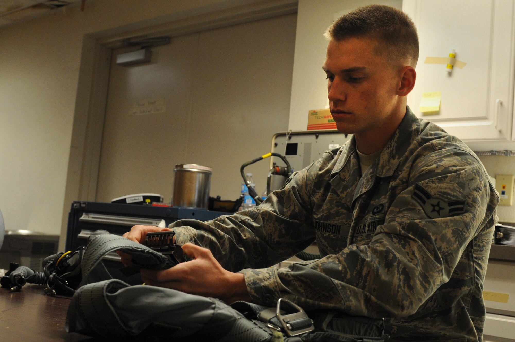 Airman 1st Class Dillon Johnson, 77th Fighter Squadron aircrew flight equipment apprentice from Shaw Air Force Base, S.C., inspects a torso harness March 13, 2014, at Nellis AFB, Nev. Johnson worked alongside other U.S. Airmen as well as counterparts from Belgium, and Denmark to ensure flight crew equipment was serviceable during Red Flag 14-2. (Air Force photo/Staff Sgt. Chuck Broadway)