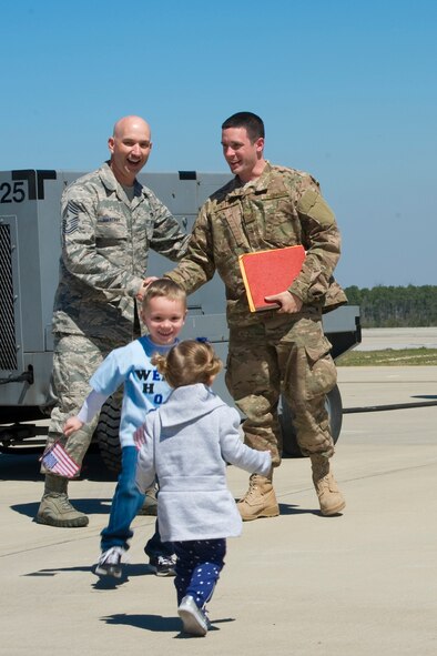 Staff Sgt. James Sweeney, 1st Special Operations Component Maintenance Squadron electronic warfare technician, is greeted by Chief Master Sgt. Jeffery Maberry,1st Special Operations Wing command chief and his two children on the flightline at Hurlburt Field, Fla., March 13, 2014. During OpHo, base leadership and families welcome Air Commandos on their return from deployment. (U.S. Air Force photo/Senior Airman Naomi Griego) 