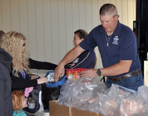 Master Sgt. Chad Hepner, 9th Aircraft Maintenance Squadron first sergeant, hands out groceries during a food drive in Penn Valley, Calif., March 11, 2014. Hepner and other Beale first sergeants helped palletize and then distribute thousands of pounds of goods to more than 120 families. (U.S. Air Force photo by Staff Sgt. Robert M. Trujillo/Released)