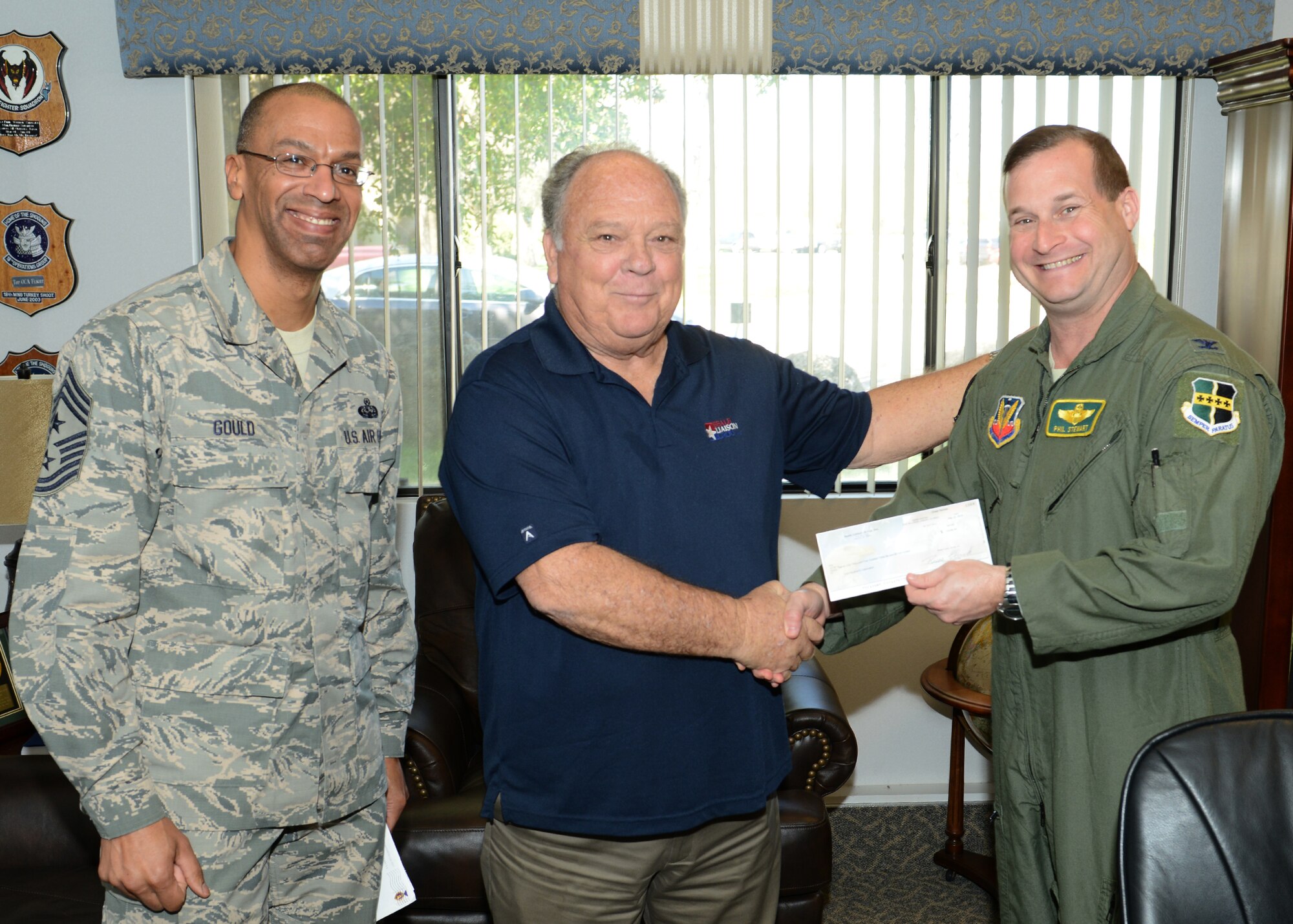 Beale Military Liaison Group member Bill Simmons presents Col. Phil Stewart, 9th Reconnaissance Wing commander, with a check of more than $21,000 in honor of Operation Warm Heart, March 12, 2014. In 2013, the BMLG donated more than $108,000 for quality of life projects for Beale Airmen. (U.S. Air Force photo by John Schwab/Released)     