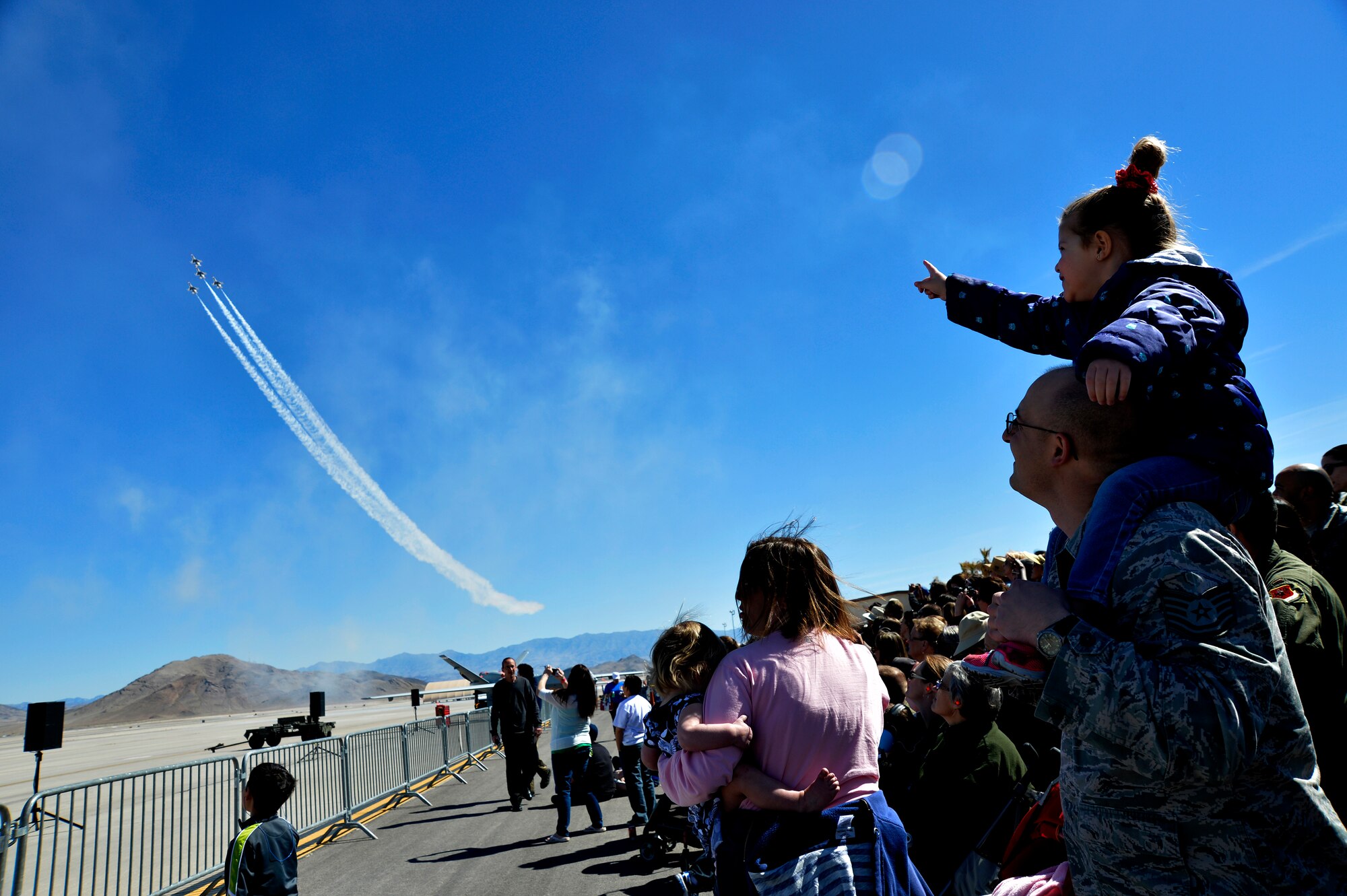 Amelia, daughter of Tech. Sgt. Chris, points at the U.S. Air Force Thunderbirds as they fly in front of the crowd during Indian Springs Appreciation Day March 11, 2014, at Creech Air Force Base, Nev.  The annual event gives Airmen the opportunity to showcase the base mission, aircraft, and build relationships with the Indian Springs populace. (U.S. Air Force photo by Staff Sgt. A.K./Released)