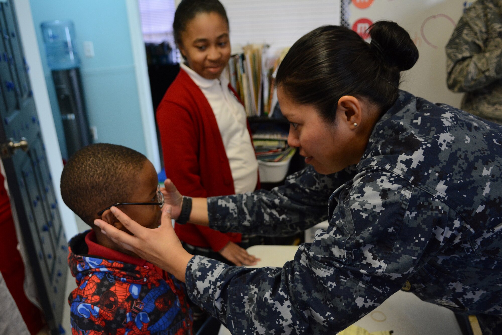 Hospital Corpsman 2nd Class Ana Chacon, Operational Health Support Group San Diego optometry technician, adjusts a Lighthouse Christian Academy student’s new glasses during Cajun Care 2014 in Abbeville, La., March 6, 2014. Air National Guard and Navy personnel visited the school to examine the students' and teachers' eyes, and later returned with glasses for all who needed them. (Air National Guard photo by Senior Airman Andrea F. Liechti)