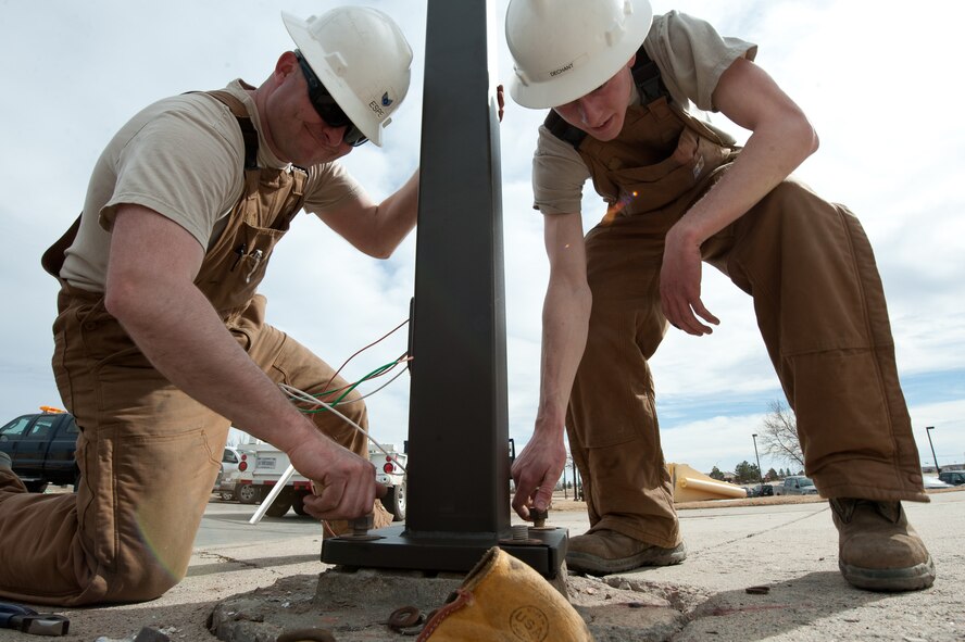 Staff Sgt. Adam Espe and Airman 1st Class Daniel Dechant, 28th Civil Engineer Squadron electrical systems technicians, secure the base of a newly-installed street light with screws at Ellsworth Air Force Base, S.D., March 10, 2014. Airmen from the 28th CES replaced more than nine streets lamps that were damaged by cold weather and high winds. (U.S. Air Force photo by Senior Airman Alystria Maurer/Released)