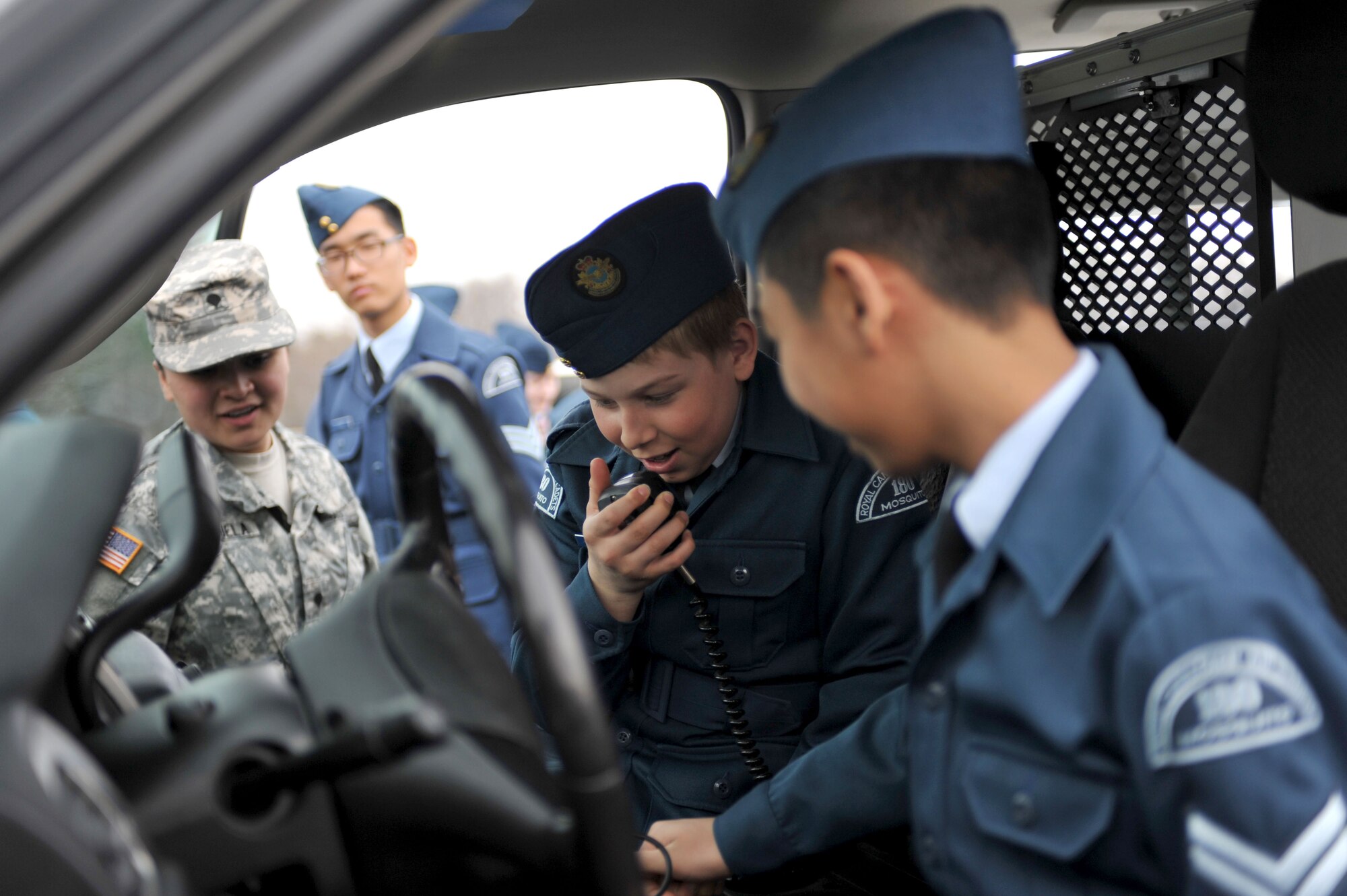 U.S. Army Spc. Roxanne Cavezuela, left, 3rd Military Police Detachment military working dog handler, explains patrol car equipment to Canadian Air Cadets from the 180th Mosquito Squadron at Fort Eustis, Va., March 12, 2014. The cadets toured the U.S. Army Transportation Museum, 128th Aviation Brigade and 7th Transportation Brigade (Expeditionary) vessels at 3rd Port. (U.S. Air Force photo by Staff Sgt. Katie Gar Ward/Released)