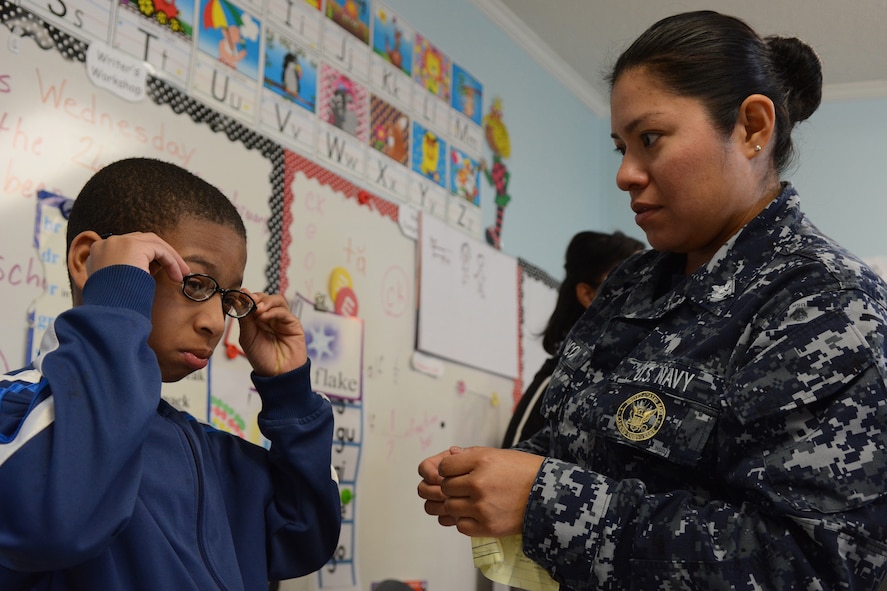 Hospital Corpsman 2nd Class Ana Chacon, Operational Health Support Group San Diego optometry technician, gives a pair of glasses to one of the Lighthouse Christian Academy students during Cajun Care 2014 in Abbeville, La., March 6, 2014. Air National Guard and Navy personnel visited the school to examine the students' and teachers' eyes, and later returned with glasses for all who needed them. (Air National Guard photo by Senior Airman Andrea F. Liechti)