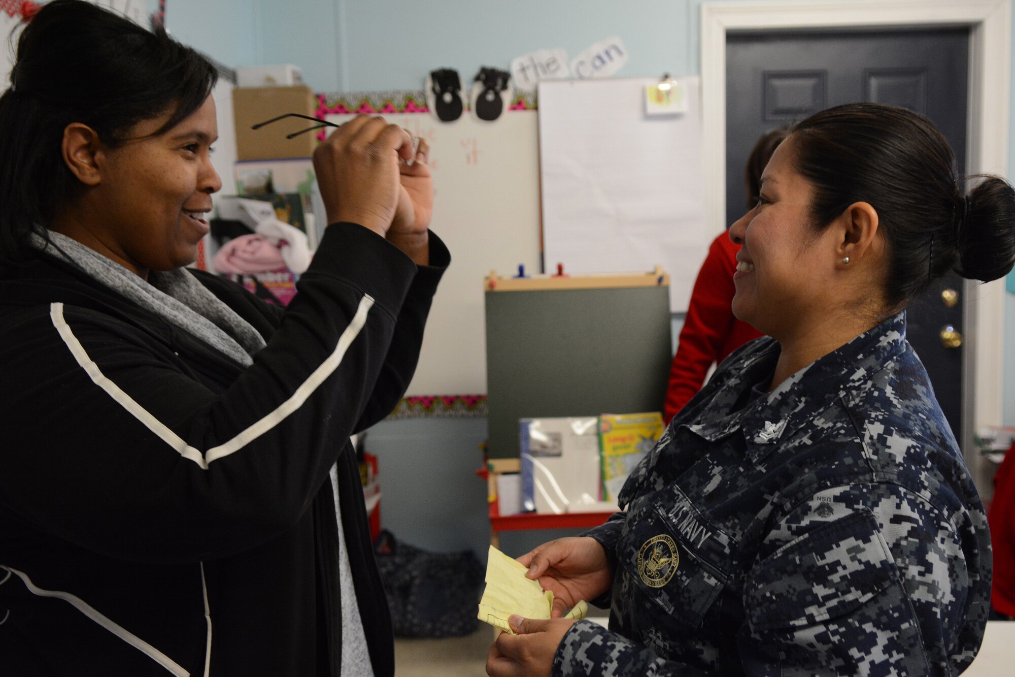 Hospital Corpsman 2nd Class Ana Chacon, Operational Health Support Group San Diego optometry technician, gives a pair of glasses to one of the Lighthouse Christian Academy teachers during Cajun Care 2014 in Abbeville, La., March 6, 2014. Air National Guard and Navy personnel visited the school to examine the students' and teachers' eyes, and later returned with glasses for all who needed them. (Air National Guard photo by Senior Airman Andrea F. Liechti)