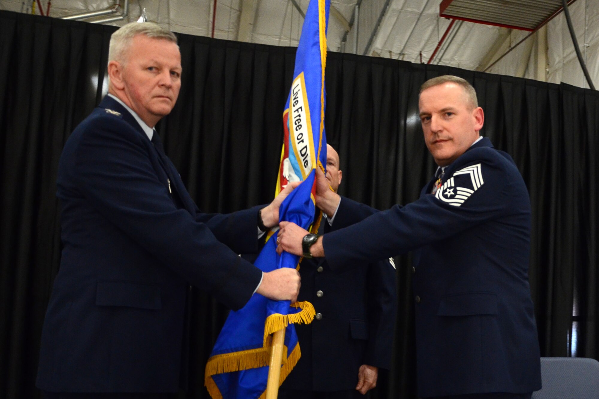 PEASE AIR NATIONAL GUARD BASE, N.H. -- 157th Air Refueling Wing Commander Col. Paul Hutchinson passes the wing flag to Chief Master Sgt. Jamie Lawrence upon appointment as the new wing command chief. Lawrence replaces Chief Master Sgt. Brenda Blonigen who served in the position for more than five years. Lawrence's previous role was as the 66th Force Support Squadron superintendent. (N.H. National Guard photo by Tech. Sgt. Mark Wyatt/RELEASED)