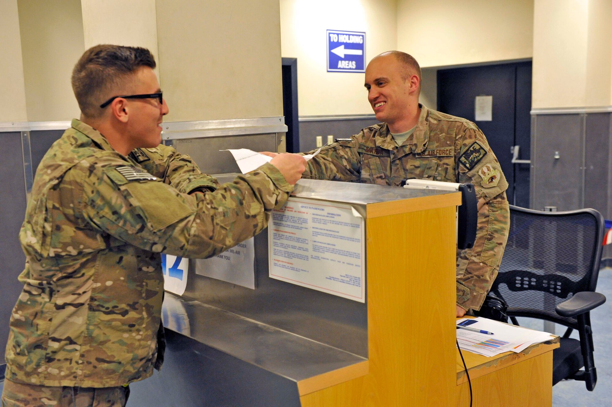 U.S. Air Force Airman 1st Class Stephen Marra assists a traveler at the passenger terminal at Bagram Airfield, Afghanistan, Feb. 27, 2014. Marra was deployed from the 109th Airlift Wing, New York Air National Guard.(U.S. Air Force photo by Senior Master Sgt. Gary J. Rihn/Released)