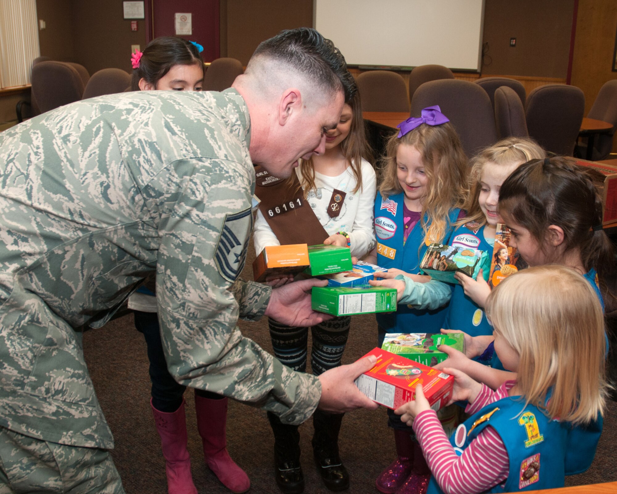 HANSCOM AIR FORCE BASE, Mass. – Master Sgt. Shon Teicheira, 66th Force Support Squadron Family Readiness coordinator, accepts Girl Scout cookies from members of Hanscom’s Girl Scout Daisy Troop at the Airman and Family Readiness Center March 12. These cookies were the initial donation of 200 cases that will be sent to deployed servicemembers. (U.S. Air Force photo by Mark Herlihy)