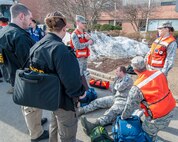 HANSCOM AIR FORCE BASE, Mass. – During a base readiness exercise, (left to right in orange vests) Senior Airman Ryan K. Springer, Maj. Julie A. Freilino and Senior Airman Benjamin L. Powell, 66th Medical Squadron medics tend to Master Sgt. Michael McGeever, 66th Air Base Group Legal Office superintendent and injured role player in an active shooter scenario, outside Building 1606 March 11. Office of Special Investigations Special Agents Anthony Salpino and Nicole Boucher, prepare to question the injured sergeant as part of the scenario that tested the installation’s readiness to respond to an active shooter. (U.S. Air Force photo by Rick Berry)