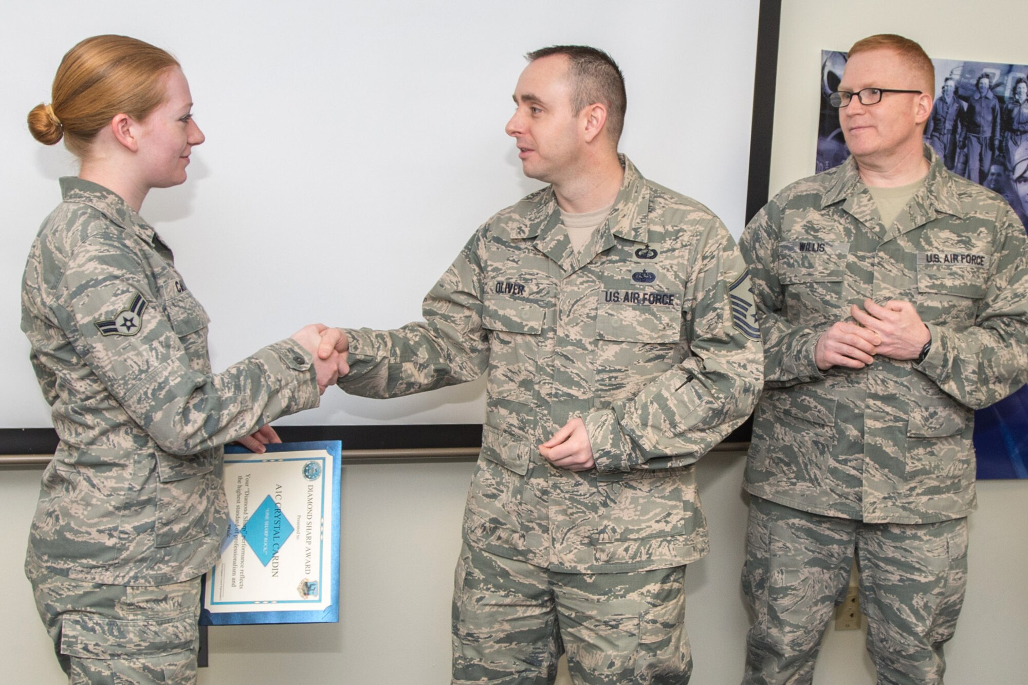 HANSCOM AIR FORCE BASE, Mass. – Hanscom first sergeants present Airman 1st Class Crystal Cardin the Diamond Sharp Award in the Brown Building March 6. From left to right, Cardin, 66th Comptroller Squadron, Master Sgt. Jason L. Oliver, 66th Air Base Group first sergeant and Master Sgt. Stephen Willis, 66th Security Forces Squadron first sergeant selected Cardin as the recipient of the Diamond Sharp Award for performance reflecting the highest standard of professionalism and pride. (U.S. Air Force photo by Rick Berry)