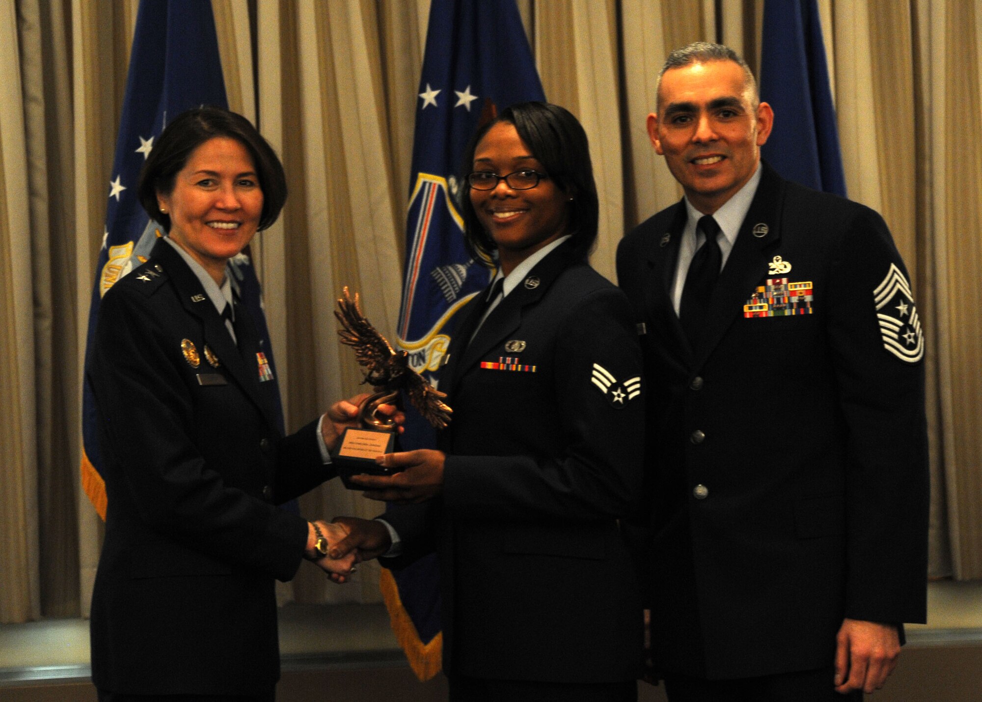 Senior Airman Chelsea Jordan accepts the 2013 Air Force District of Washington Headquarter Staff Annual Awards Military Volunteer of the Year trophy from AFDW Commander Maj. Gen. Sharon K. G. Dunbar and AFDW Command Chief Master Sgt. Jose LugoSantiago during the awards ceremony at Joint Base Andrews, Md., March 4, 2014. Jordan is a member of the AFDW Financial Management Office. (U.S. Air Force photo/Master Sgt. Tammie Moore)
