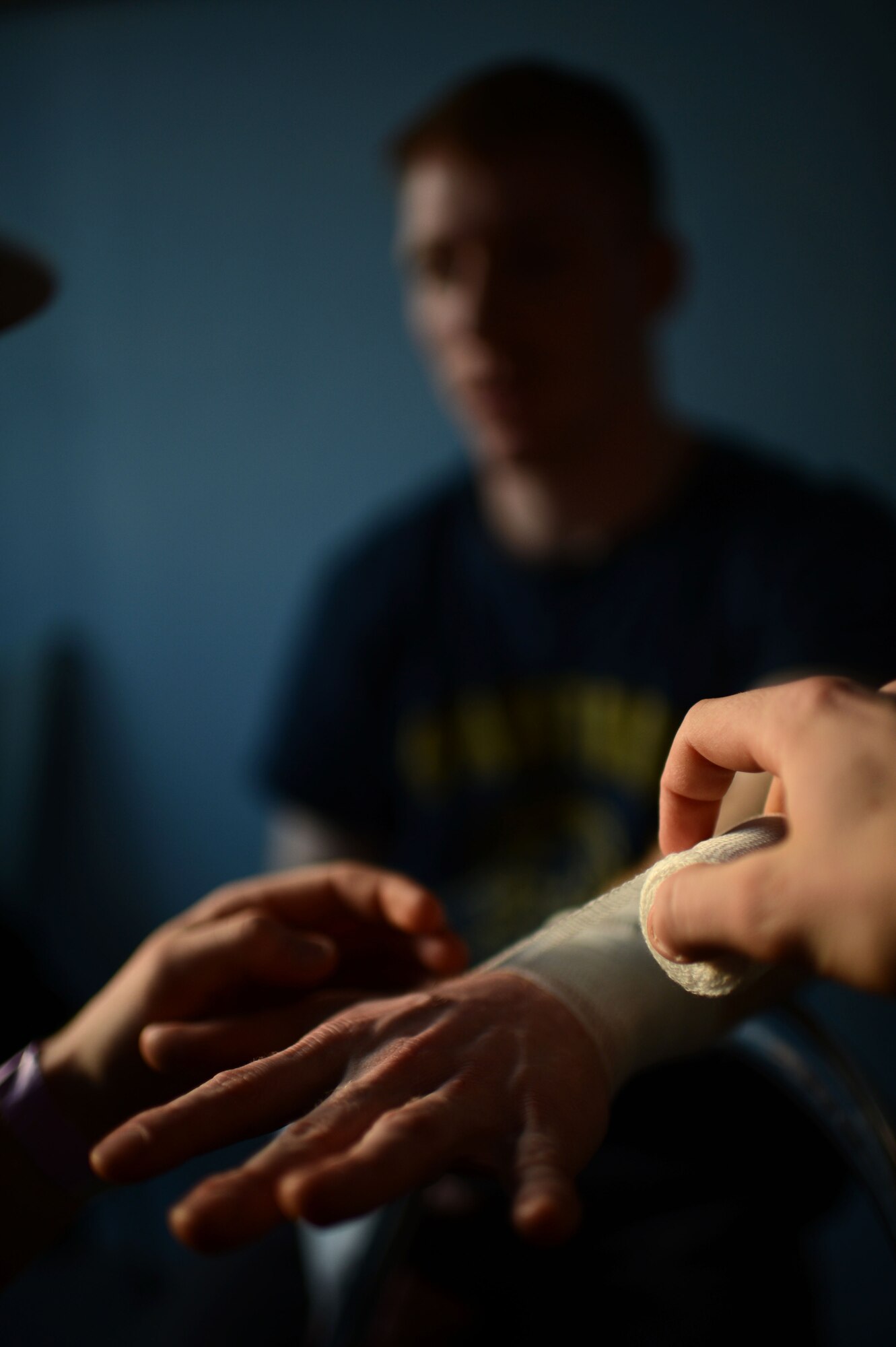 U.S. Air Force Senior Airman Cody Hughes, a Spangdahlem mixed martial arts member from Bakersfield, Calif., tapes the hands of teammate U.S. Air Force Senior Airman Sean Whitaker from Pittsburgh, before his match at an MMA tournament in Pruem, Germany, March 8, 2014. Fighters tape their hands and wrists as a safety precaution against breaking bones during a match. (U.S. Air Force photo by Senior Airman Gustavo Castillo/Released) 