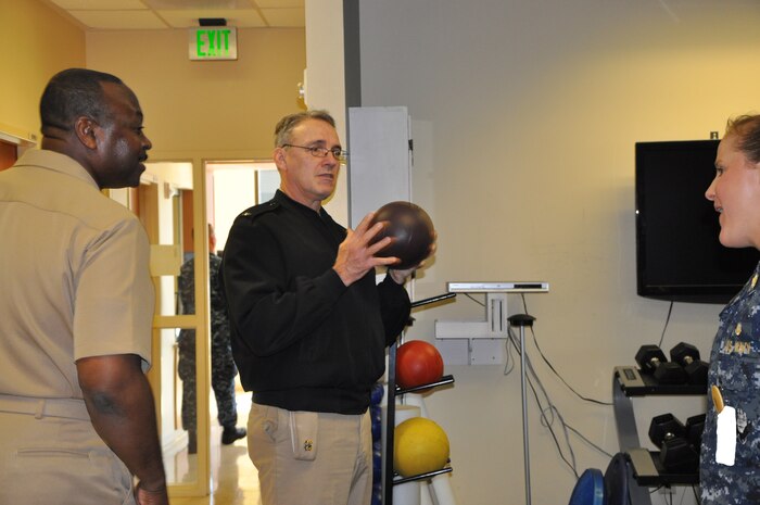 Navy Rear Adm. Rick Williamson, Commander of Navy Region Southeast, discusses physical therapy techniques and methods with Navy Lt. Lauren Brown, Naval Health Clinic Charleston physical therapist, during a visit to the clinic Tuesday. NHCC's Commanding Officer Capt. Marvin Jones, left, gave Williamson a tour of NHCC, which provides a wide range of primary, specialty, ancillary and occupational health services for service members, family members and veterans of Joint Base Charleston - Weapons Station. (Photo by Petty Officer 3rd Class Caralyn Mulyk, NHCC Public Affairs)
