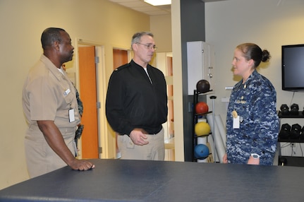 Navy Rear Adm. Rick Williamson, Commander of Navy Region Southeast, discusses physical therapy techniques and methods with Navy Lt. Lauren Brown, Naval Health Clinic Charleston physical therapist, during a visit to the clinic Tuesday. NHCC's Commanding Officer Capt. Marvin Jones, left, gave Williamson a tour of NHCC, which provides a wide range of primary, specialty, ancillary and occupational health services for service members, family members and veterans of Joint Base Charleston - Weapons Station. (Photo by Petty Officer 3rd Class Caralyn Mulyk, NHCC Public Affairs)