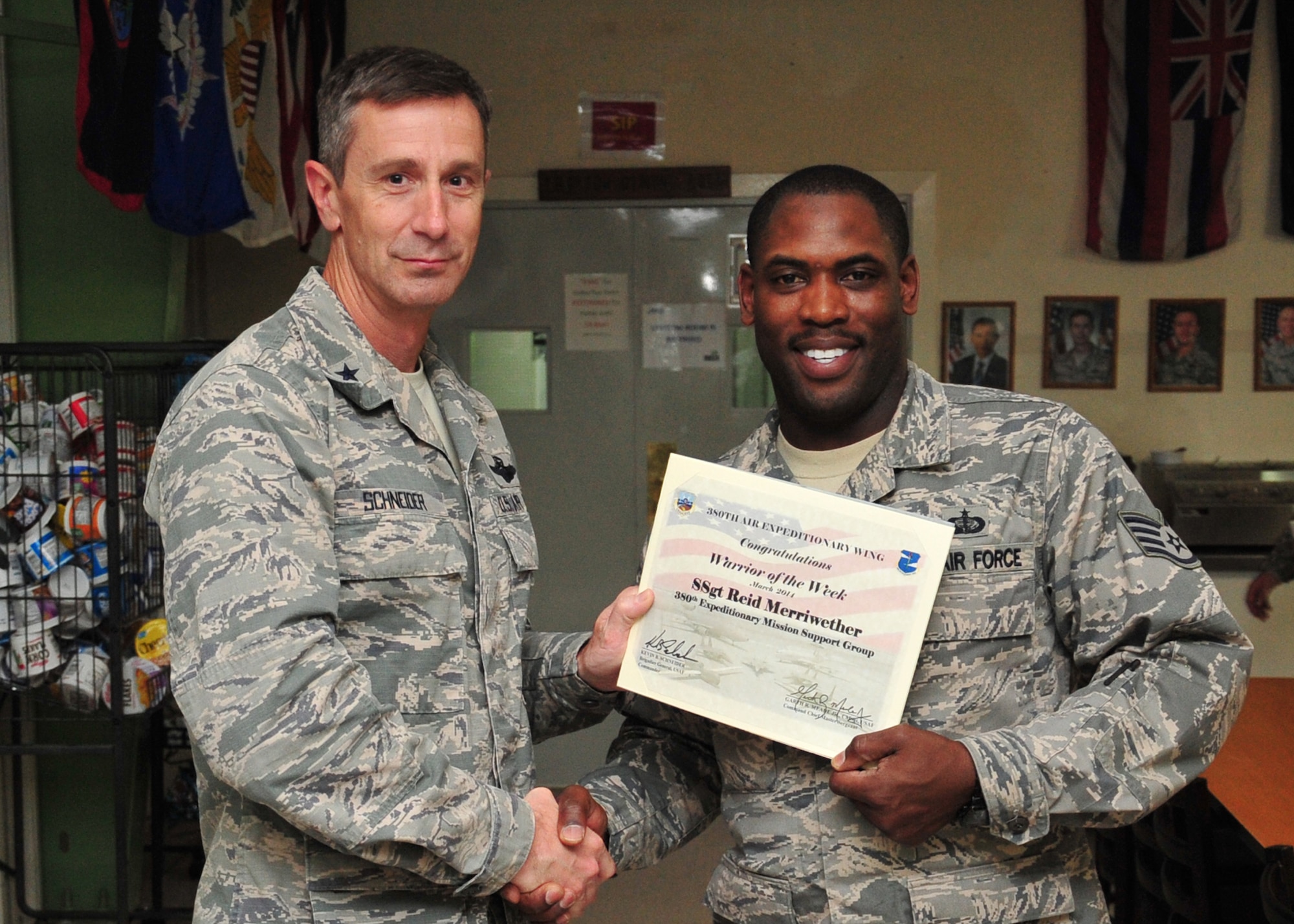 Air Force Brig. Gen. Kevin Schneider, 380th Air Expeditionary Wing commander, presents Air Force Staff Sgt. Reid Merriwether, 380th Expeditionary Force Support Squadron Food Accountant and Special Events coordinator, a warrior of the week certificate at an undisclosed location in Southwest Asia, March 12, 2014.  Merriwether is a native of Indianapolis, Ind., and is deployed from Shaw Air Force Base S.C.