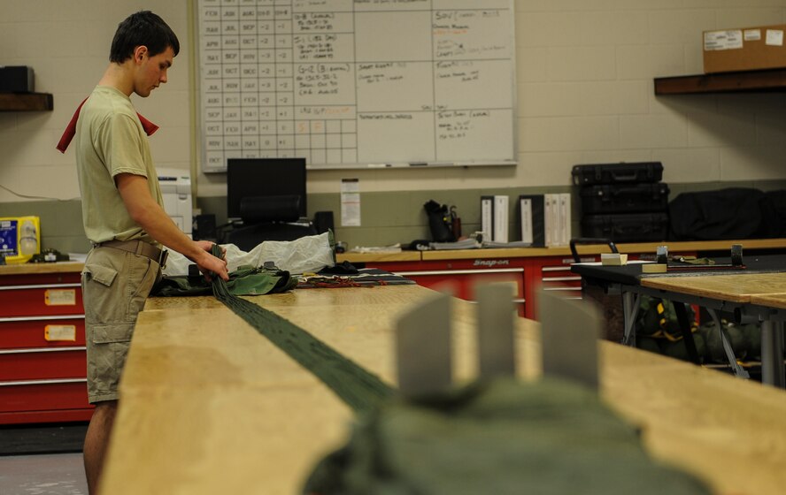 U.S. Air Force Airman 1st Class Dallas Remonda, 38th Rescue Squadron aircrew flight equipment apprentice, stows suspension lines on a parachute at Moody Air Force Base, Ga., March 11, 2014. On an average, AFE packs about 50 parachutes a week. (U.S. Air Force photo by Airman 1st Class Alexis Millican/Released)