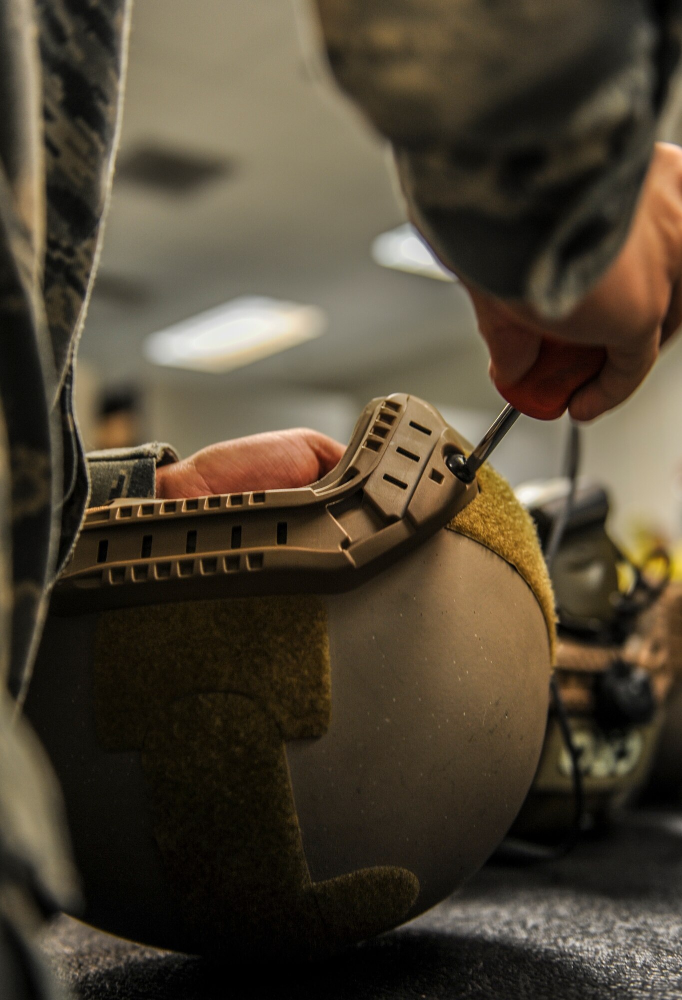 U.S. Air Force Airman 1st Class Matthew Gomez, 38th Rescue Squadron aircrew flight equipment apprentice, changes out the chinstrap on a helmet at Moody Air Force Base, Ga., March 10, 2014. In addition to helmets, aircrew flight equipment personnel also commonly work on phantom masks, parachutes, different types of binoculars and LV2 and SEA-MK2 air tanks. (U.S. Air Force photo by Airman 1st Class Alexis Millican/Released)