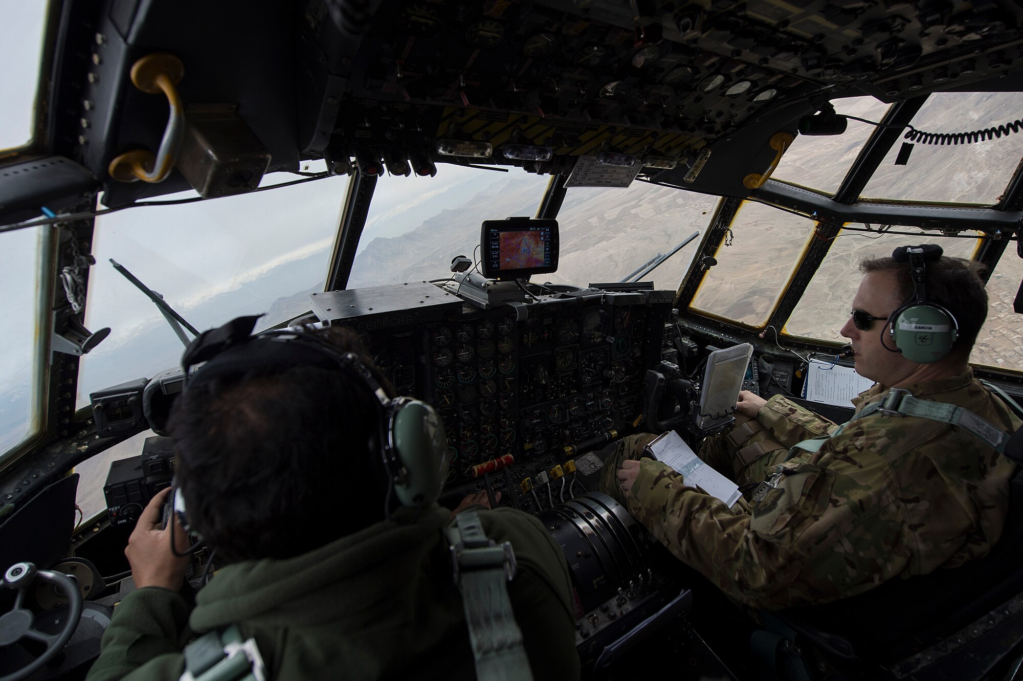 An Afghan Air Force pilot and U.S. Air Force Maj. Chris Garcia, 438th Air Expeditionary Wing/NATO Air Training Command-Afghanistan C-130 Hercules adviser, fly an advisory mission March 10, 2014, near Kabul, Afghanistan. Garcia, a Danville, Ind., native, is deployed from the 53rd Airlift Squadron, Little Rock Air Force Base, Ark. Airmen of the 438th AEW/NATC-A play a vital role in Operation Enduring Freedom as advisers tasked with aiding the Afghan government in establishing an operational and sustainable Afghan air force. (U.S. Air Force photo by Tech. Sgt. Jason Robertson/Released)