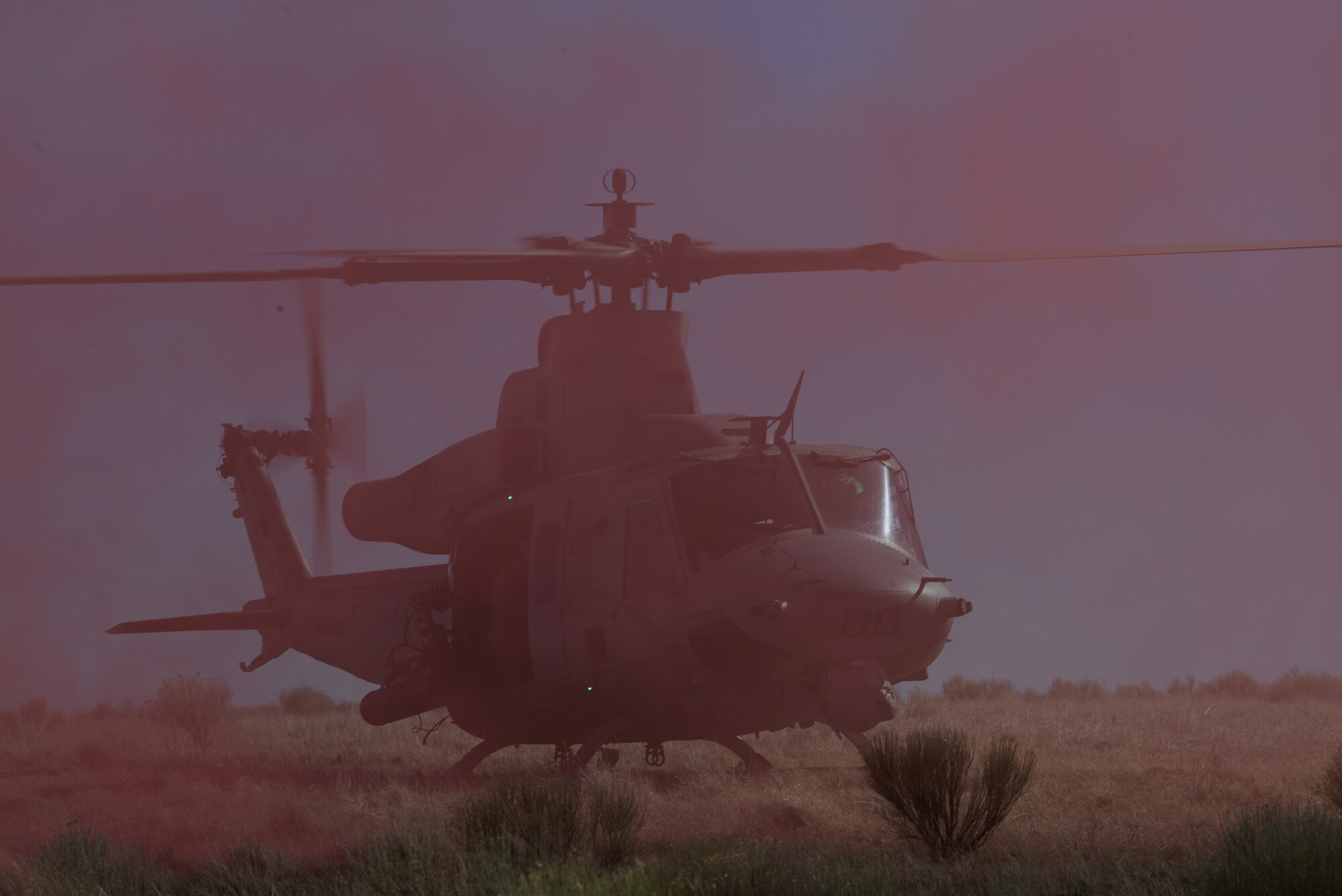 A UH-1Y Venom helicopter participating in Gunfighter Flag prepares to take-off under the cover of red smoke March 12, 2014, at the Juniper Butte Bombing Range near Mountain Home Air Force Base, Idaho. The combat exercise is designed to prepare multiple joint and coalition terminal attack controller teams for upcoming deployments as well as provide proficiency training for aircrews. (U.S. Air Force photo by Senior Airman Benjamin Sutton/Released) 
