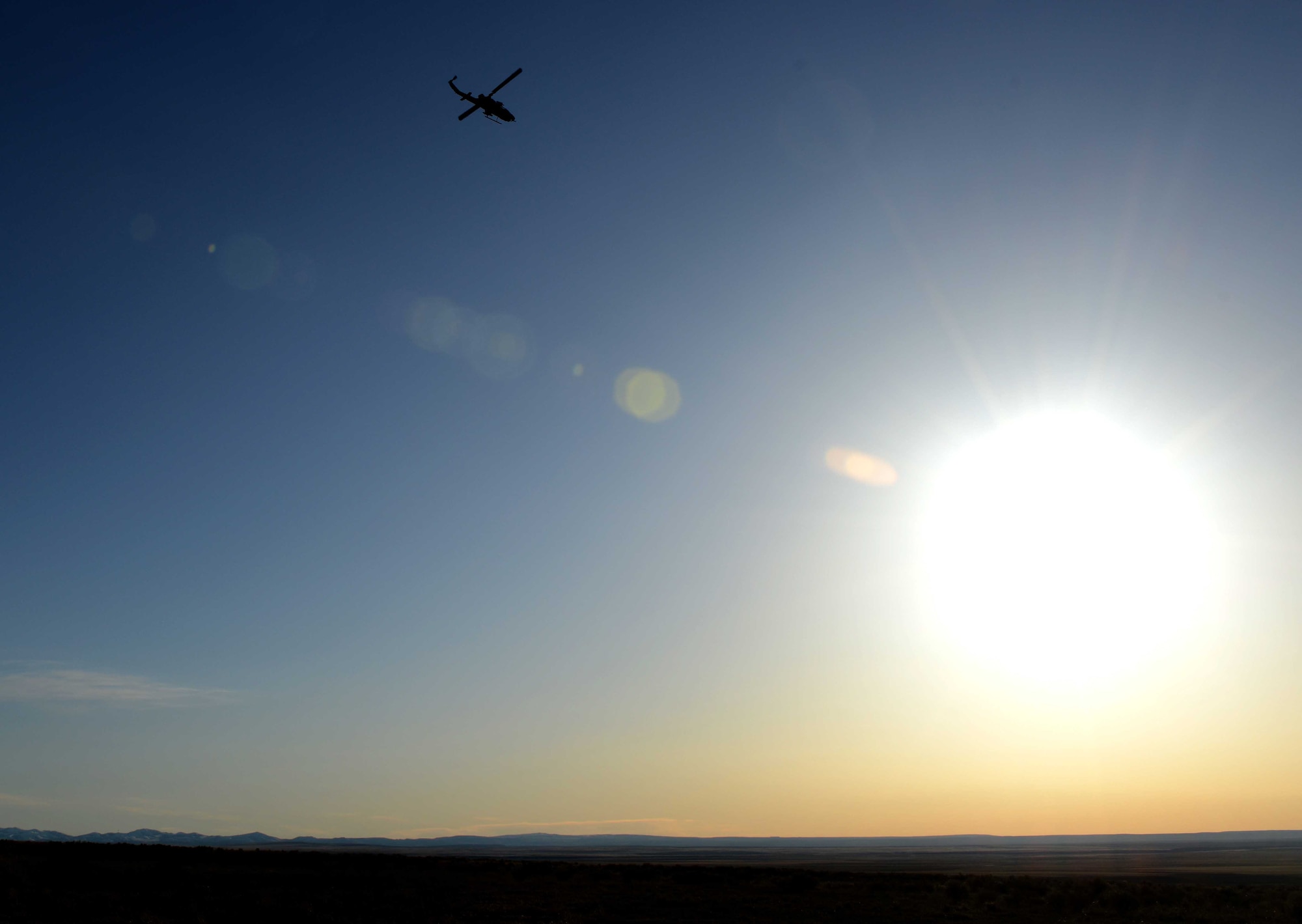 A UH-1Y Venom flies toward the setting sun after a day of training at Gunfighter Flag at the Juniper Butte Range at Mountain Home Air Force Base, Idaho, March 13, 2014. The purpose of the training is to prepare multiple joint and coalition joint terminal attack controller teams for upcoming deployments as well as provide proficiency training for aircrews. (U.S. Air Force photo by Senior Airman Caitlin Guinazu/RELEASED) 