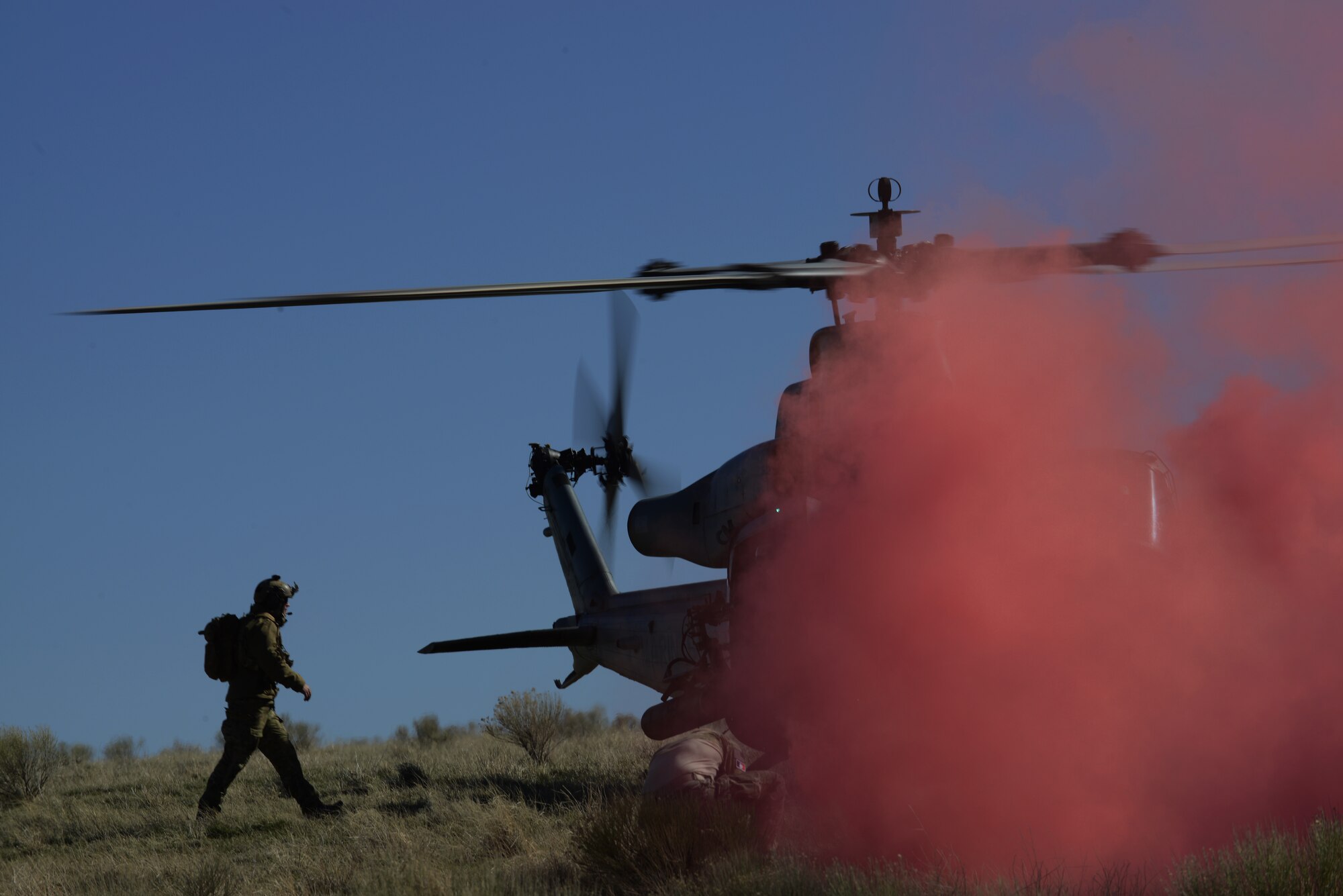 A Combat Controller moves to helicopter under the cover of red smoke March 12, 2014, at the Juniper Butte Bombing Range near Mountain Home Air Force Base, Idaho. Today’s combined-joint mix of allied ground, air and space force provides national leaders the unmatched ability to take early, rapid and decisive action in combat, peacekeeping or humanitarian operations. (U.S. Air Force photo by Senior Airman Benjamin Sutton/Released) 
