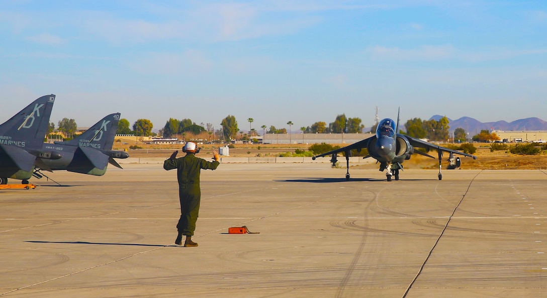 Lance Cpl. Brianna Charpi, a power line mechanic for Marine Attack Training Squadron 203, gives hand signals to Capt. Nate Thayer directing the aircraft to its proper location, on the flight line of Marine Corps Air Station Yuma, Ariz., Tues. VMAT-203’s main objective while at MCAS Yuma is to train new winged pilots like Thayer to fly the AV-8B Harrier.


