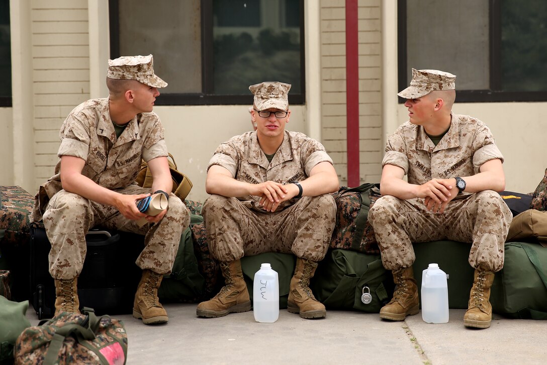 Pfc. Duane Hughes, Pvt. Johnathan Watkins and Pvt. Alex Swalley converse before boarding transportation from Marine Combat Training Battalion, Fox Compay to their Marine Occupational Specialty schools, March 11. MCT is a 29-day course where Marines are trained in standard-based combat skills to assure that "every Marine a rifleman" stands true, despite their MOS. 


