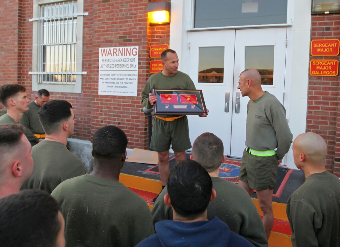 Col. Scott F. Benedict, center, the commanding officer of the 24th Marine Expeditionary Unit, delivers a unit gift to Sgt. Maj. Octaviano Gallegos Jr., the 24th Marine Expeditionary Unit sergeant major, March 14, 2014, after a unit physical training event at Camp Lejeune, N.C. Gallegos' relinquished duties as 24th MEU sergeant major later in the day to Sgt. Maj. Lanette N. Wright, who will be the first female MEU sergeant major.