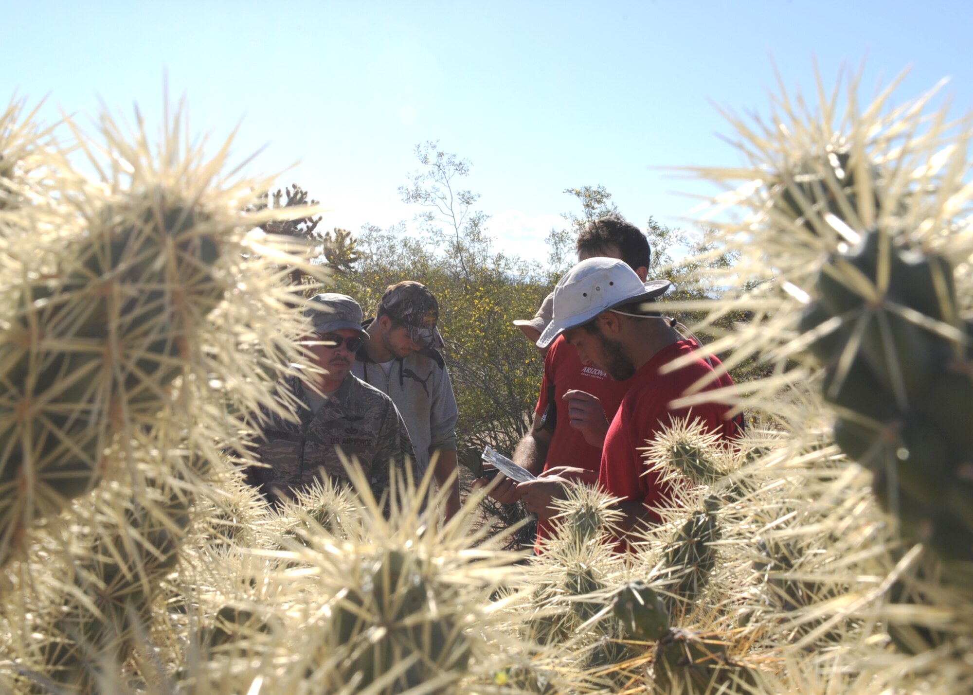 U.S. Air Force Tech. Sgt. Jamin Rendon, 55th Rescue Squadron Special Mission Aviator, assists players from the University of Arizona Rugby team during a mock search and rescue exercise at Davis-Monthan Air Force Base Ariz., March 8, 2014. The players divided into groups of six and navigated through unfamiliar terrain to rescue a simulated immobilized victim. (U.S. Air Force photo by Airman 1st Class Chris Drzazgowski/Released)