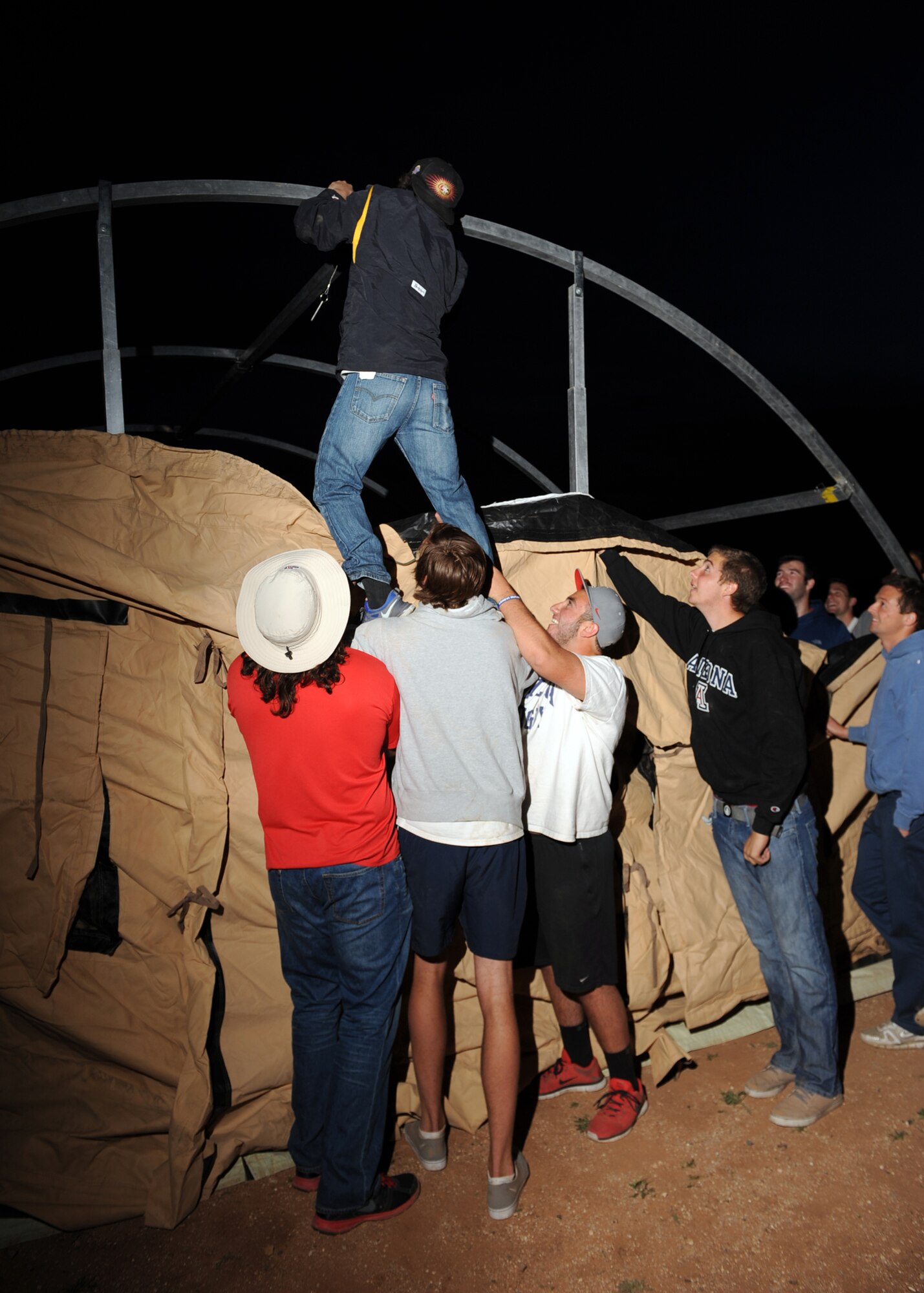 University of Arizona Rugby team players assemble an expeditionary shelter at Davis-Monthan Air Force Base, Ariz., March 7, 2014. The players were visiting the 55th Rescue Squadron for the 3rd annual Combat Wildcat event, which is geared to show the players how to work as a team through military example. (U.S. Air Force photo by Airman 1st Class Chris Drzazgowski/Released)   