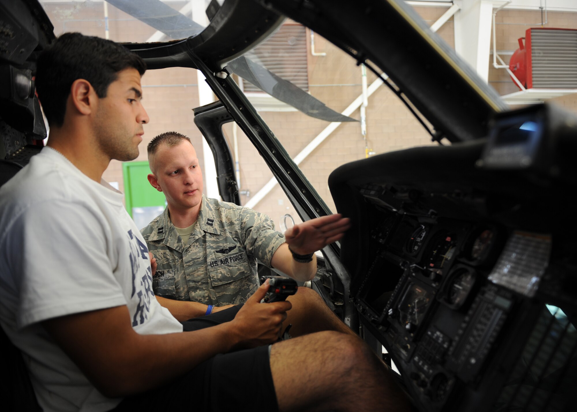U.S. Air Force Captain Jordan Wiersch, 55th Rescue Squadron HH-60G Pave Hawk pilot, describes controls and displays of an HH-60G to a member of the University of Arizona Rugby team during the 55th Rescue Squadron?s Combat Wildcat event at Davis-Monthan Air Force Base, Ariz., March 7, 2014. The HH-60G was part of a static display set up to familiarize the team members with the types of equipment used during rescue missions. (U.S. Air Force photo by Airman 1st Class Chris Drzazgowski/Released)