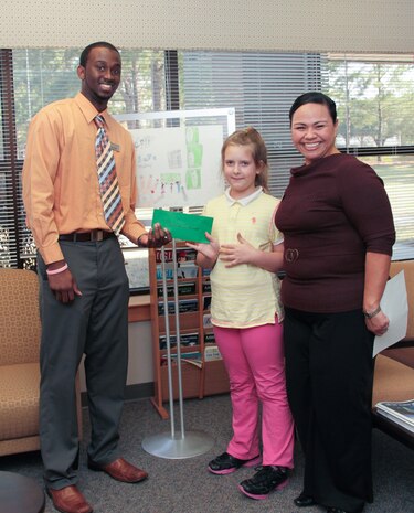 Kyla Marsh, Military Saves Youth Poster Contest Winner for Division I, is presented a $50 gift card from Navy Federal Credit Union and Heritage Trust Federal Credit Union March 11, 2014, at the Airman and Family Readiness Center on Joint Base Charleston – Air Base Charleston, S.C.  Marsh received her award from Grayland Murdock, Navy Federal Credit Union Member Services representative and Erin Brown, 628th Force Support Squadron, Fleet & Family Support Center Certified Financial counselor . 