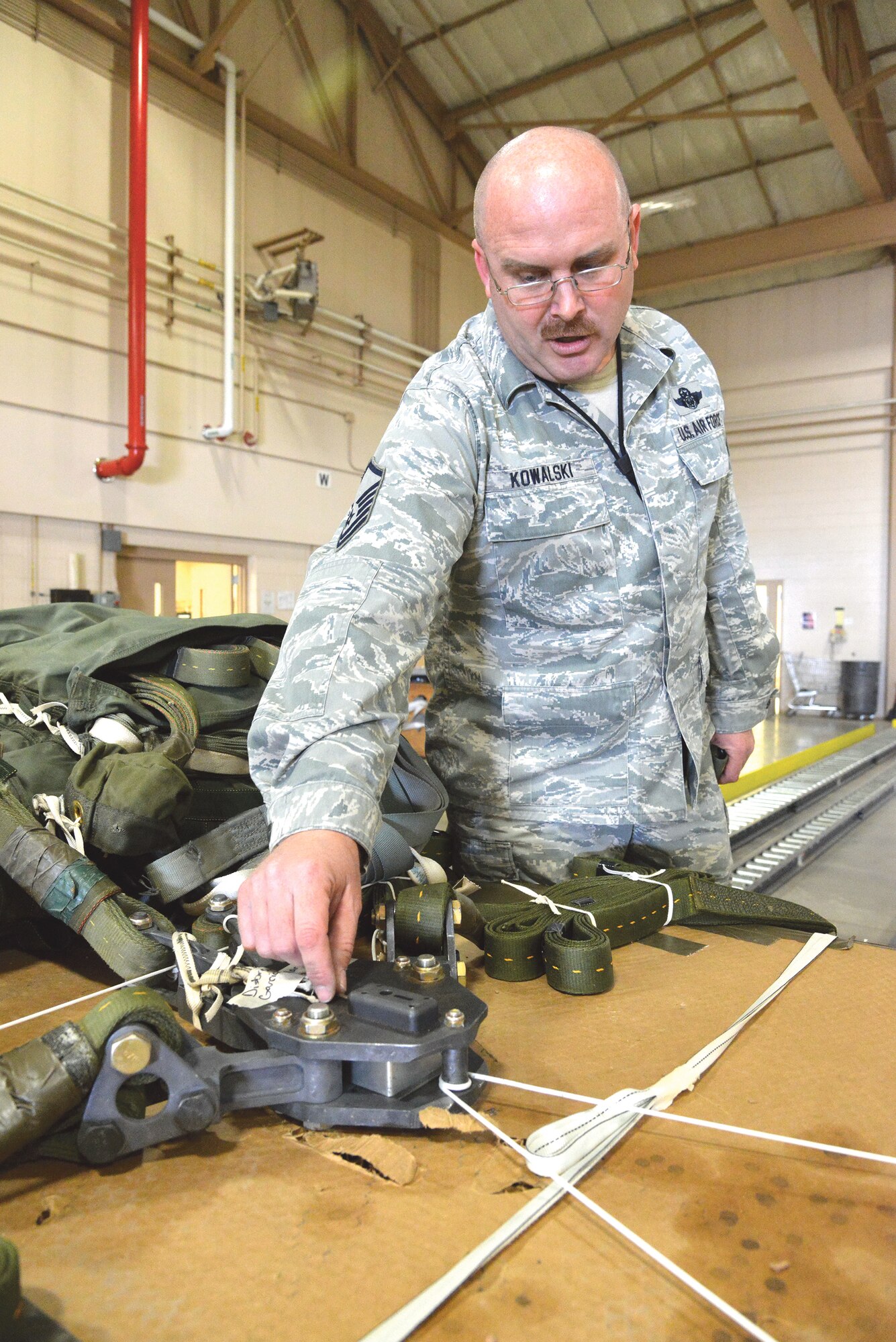 Master Sgt. Bill Kowalski, 58th Operations Support Squadron, explains one of the triggering mechanisms on a parachute package his crew prepared. (Photo by Ken Moore)