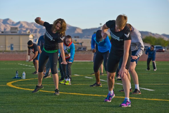 Missy Cornish, wife of Col. Barry Cornish, 99th Air Base Wing commander, leads a group during a Warrior Trained Fitness workout on the field behind the Warrior Fitness Center March 13, 2014, at Nellis Air Force Base, Nev. Warrior Trained Fitness is a high intensity interval training workout designed as a part of the "Life of a Warrior" concept of living a healthier lifestyle. (U.S. Air Force photo by Senior Airman Christopher Tam)