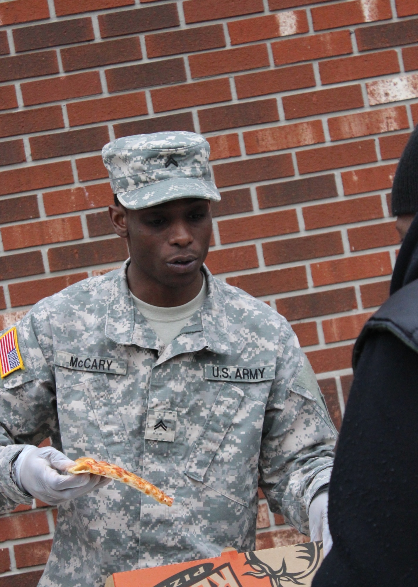 Army Sgt. Richard Saenz, observer-coach/trainer with the 2-312th Regiment, 174th Infantry Brigade, serves slices of pizza to the homeless in Camden, N.J., March 2, 2014. Saenz, originally from Camden, collected donations from 2-312th Soldiers to purchase the pies. (U.S. Army courtesy photo by Sgt. Richard Saenz/Released)
