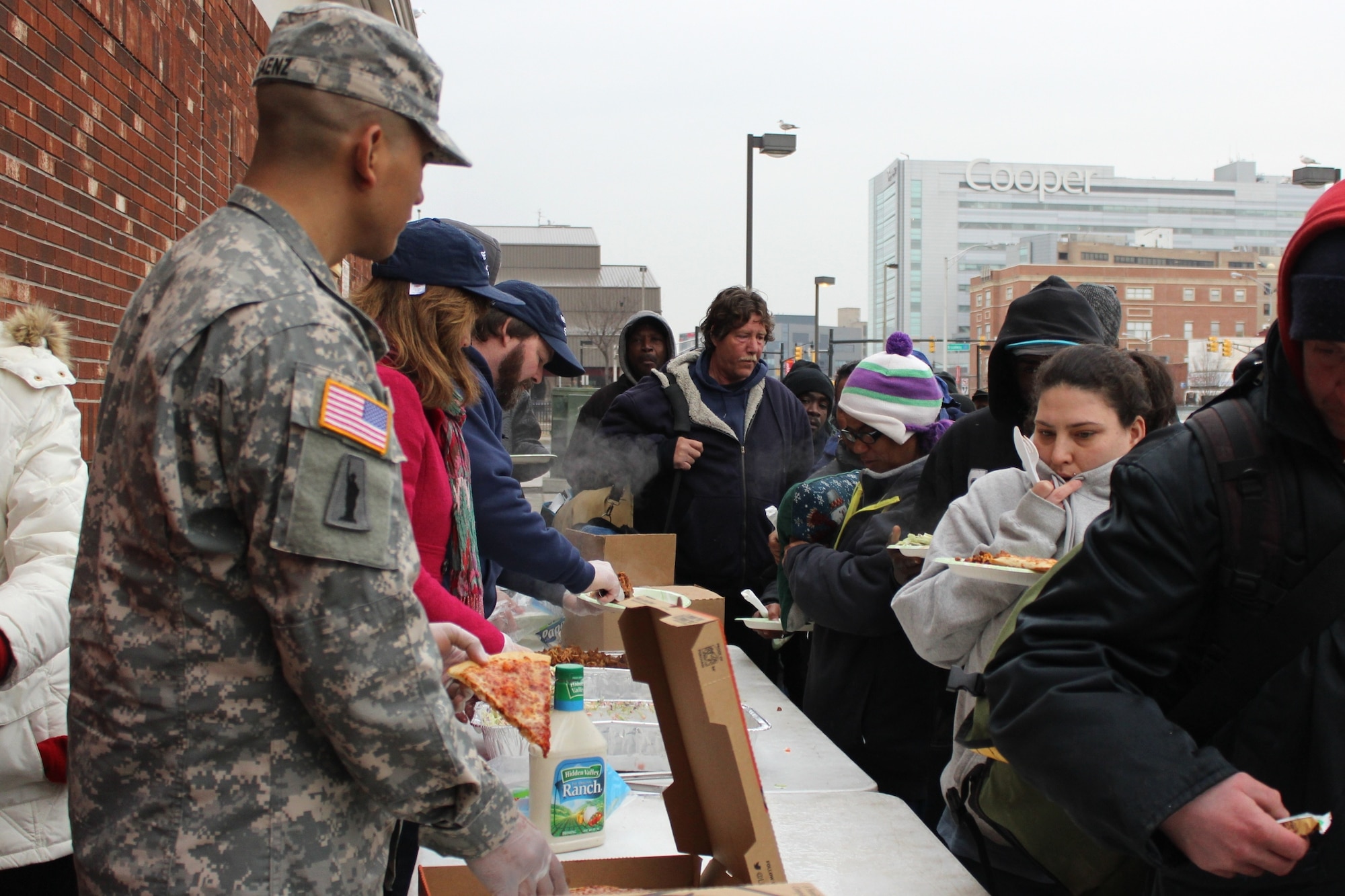 Army Sgt. Richard Saenz, observer-coach/trainer with the 2-312th Regiment, 174th Infantry Brigade, serves slices of pizza to the homeless in Camden, N.J., March 2, 2014. Saenz, originally from Camden, collected donations from 2-312th Soldiers to purchase the pies. (U.S. Army courtesy photo by Sgt. Richard Saenz/Released)