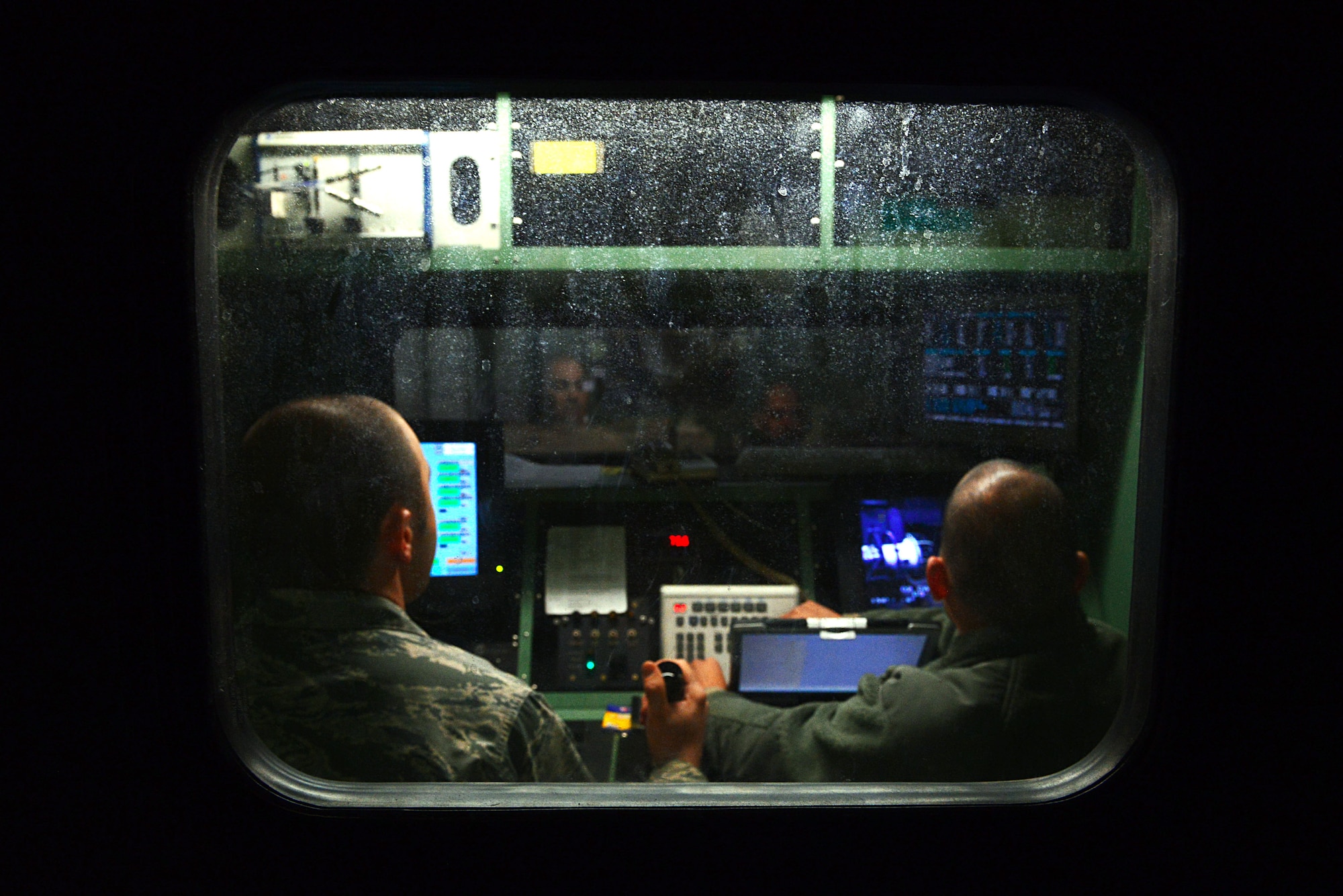 [From left] U.S. Air Force Staff Sgt. Samuel Allen and Senior Airman Sigfredo Mongevillanueva, 20th Component Maintenance Squadron jet engine craftsmen, prepare to start a jet engine inside a control booth at the engine test facility, Shaw Air Force Base, S.C., March 13, 2014. Two computers inside the booth give exact measurements of temperature, vibration and fuel pressure from the jet engine while fuel is injected into the engine. (U.S. Air Force photo by Airman 1st Class Jensen Stidham/Released)
