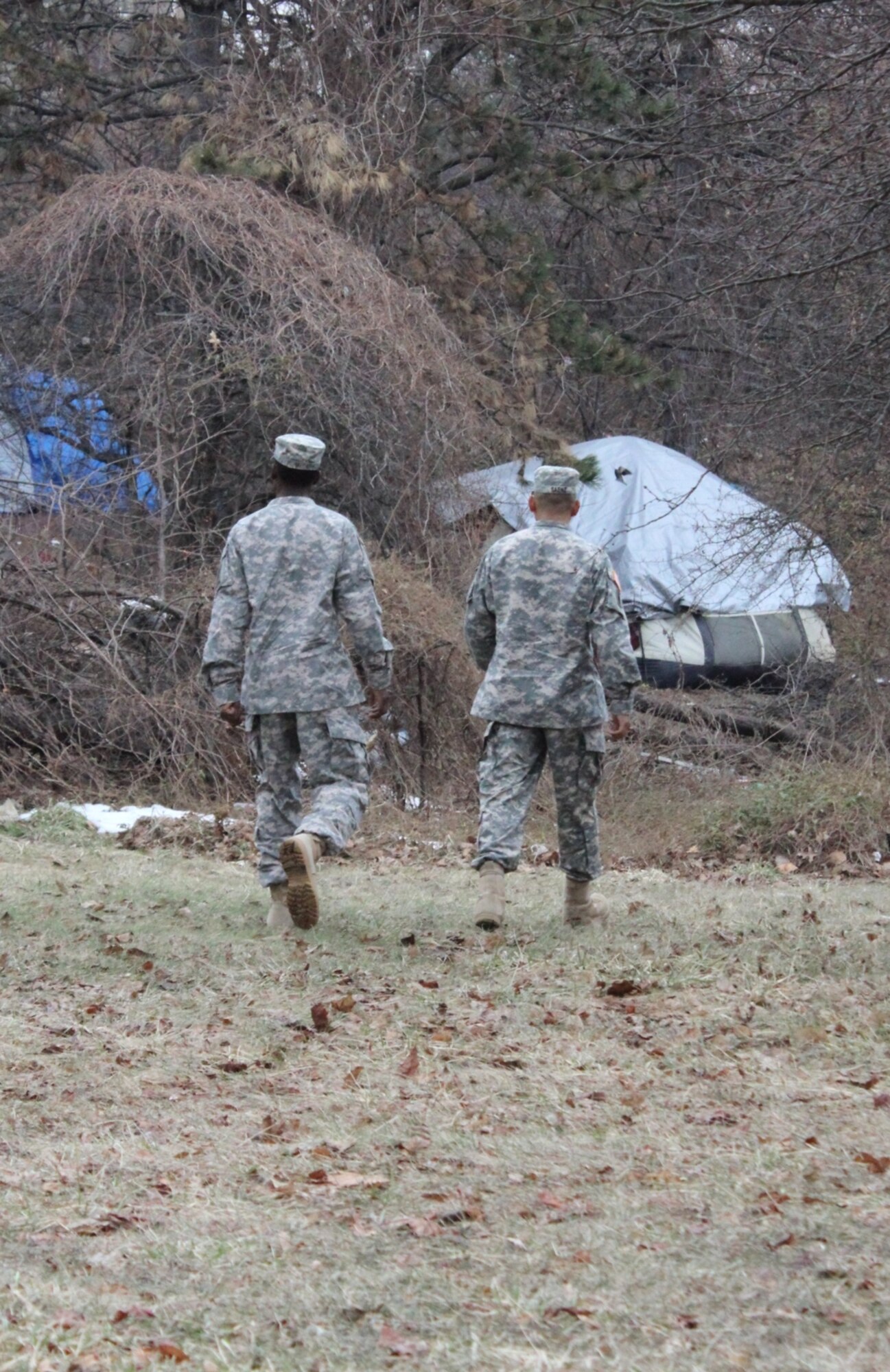 Army Cpl. Derno McCary and Army Sgt. Richard Saenz, observer-coach/trainers with the 2-312th Regiment, 174th Infantry Brigade, approach a tent compound in Camden, N.J., March 2, 2014, to check for occupants taking shelter from the cold. Both Soldiers drove to the city from Joint Base McGuire-Dix-Lakehurst to spend their off-duty time providing donated pizzas to the homeless. (U.S. Army courtesy photo by Sgt. Richard Saenz/Released)