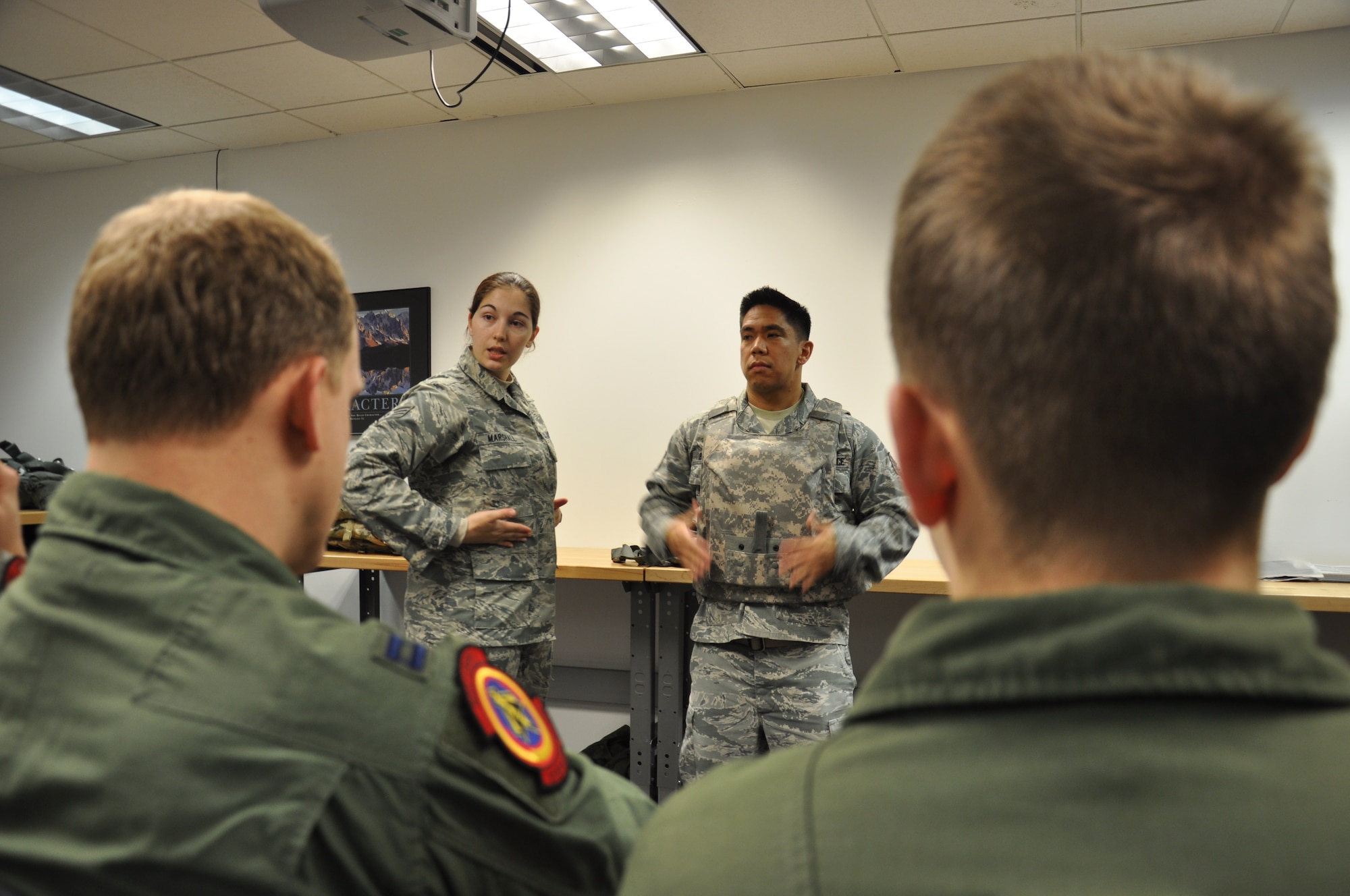 Staff Sgt. Iva Marshall and Tech. Sgt. Arvin Baldorado, both 60th Operations Support Squadron Aircrew Flight Equipment technicians, demonstrate to aircrew how to fit the plate carrier vest of one of the integrated body armor systems March 4. Travis AFE Airman and aircrew tested and evaluated two integrated aircrew body armor systems for a week on Travis aircraft. (U.S. Air Force photo/Staff Sgt. Christopher Carranza)