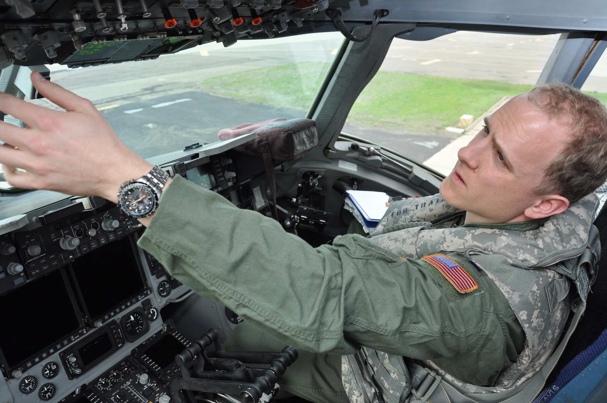Capt. Eric Deist, 21st Airlift Squadron pilot, reaches for the control panel while wearing an integrated aircrew body armor system to assess movement restrictions during pre-flight checks aboard a C-17 Globemaster III March 4 on the flightline. Diest said that after performing the tests and evaluations of the program, he understands the value of testing the equipment. (U.S. Air Force photo/Staff Sgt. Christopher Carranza)